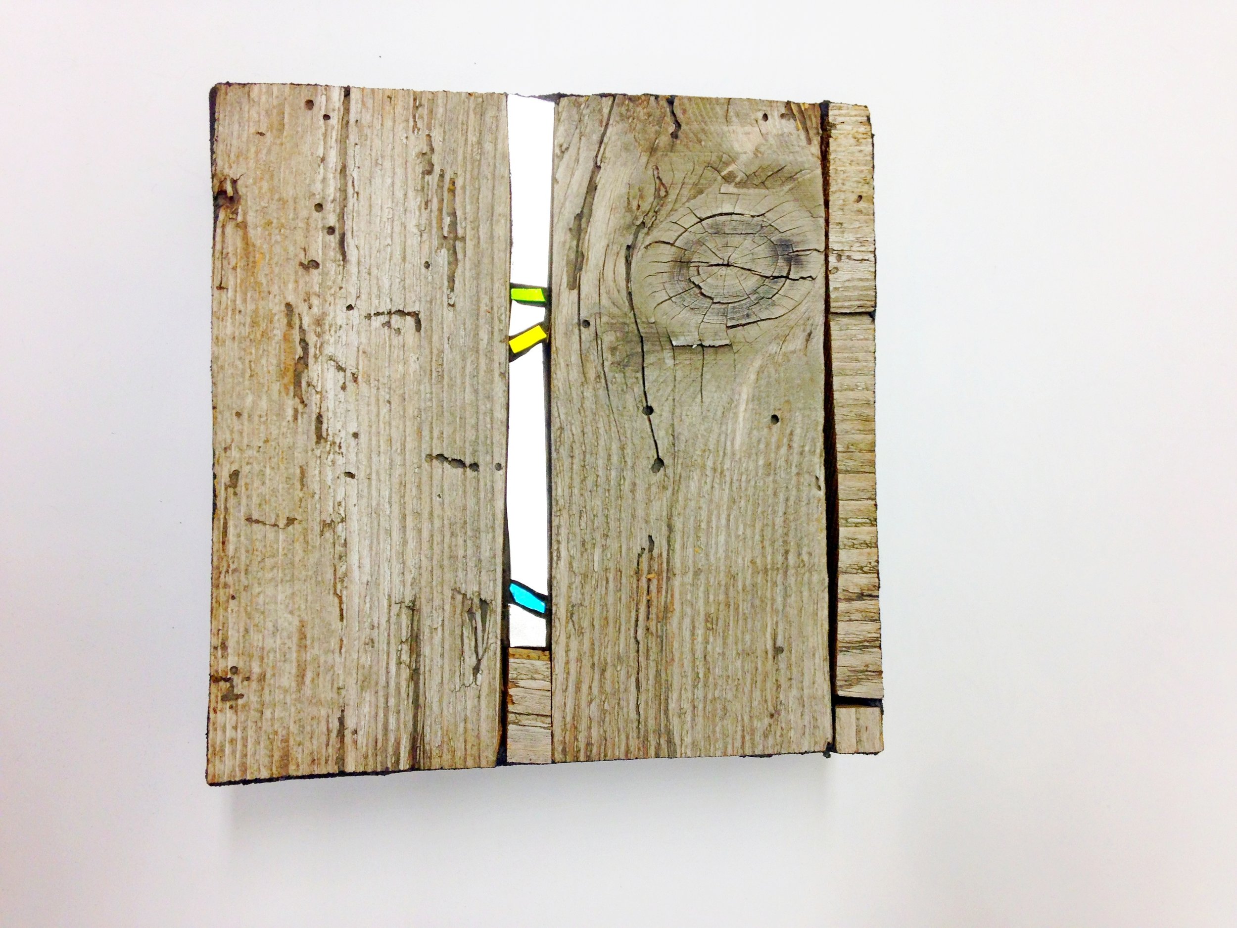 Trois planches de bois avec des trous et des fissures, elles sont empilées contre un fond blanc.