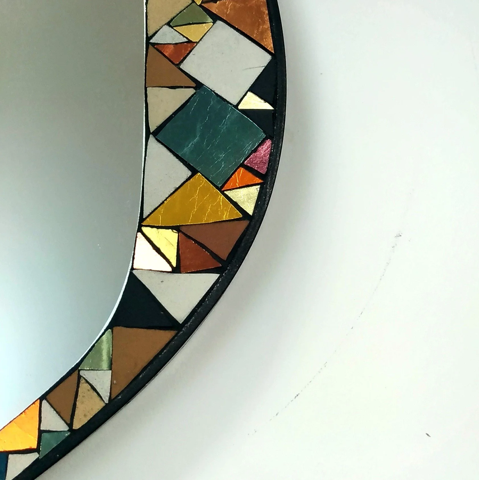 Détails d'un miroir en mosaïque coloré avec des formes géométriques dans un cadre noir