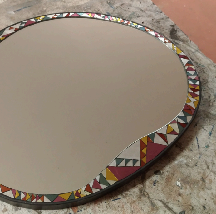 Miroir en mosaïque de couleur automnale avec un cadre coloré de triangles et autres formes géométriques.