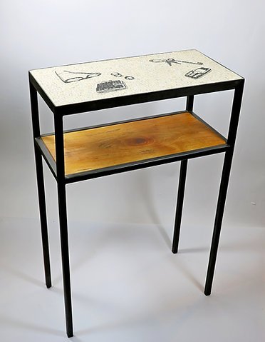 Table avec un plateau supérieur décoré avec des dessins d'outils, et une étagère inférieure en bois.