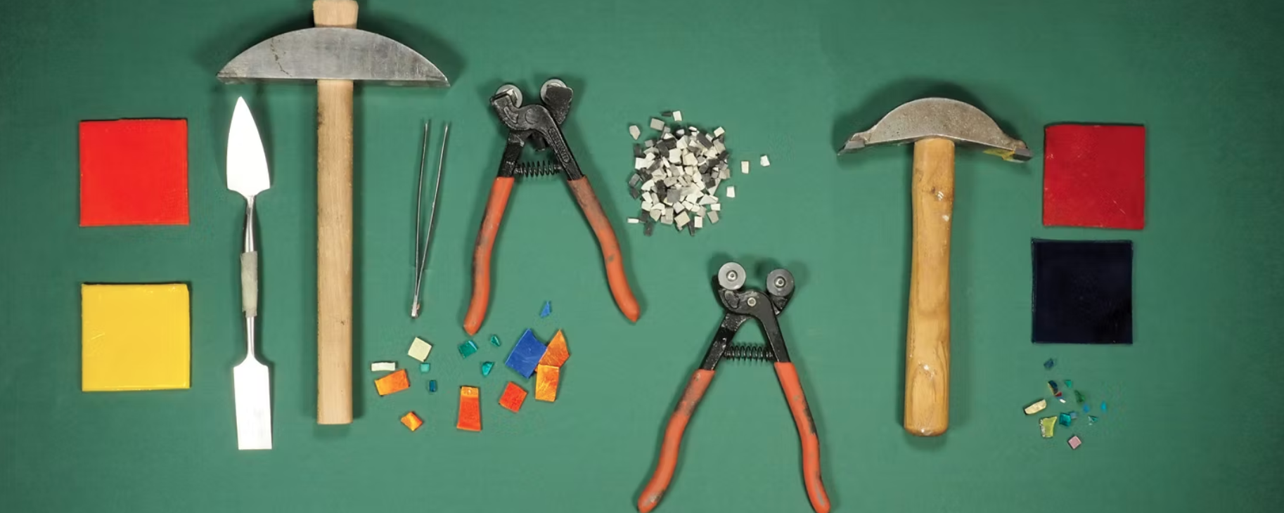 Outils pour mosaïque et fragments de mosaïque colorée sur un fond vert.