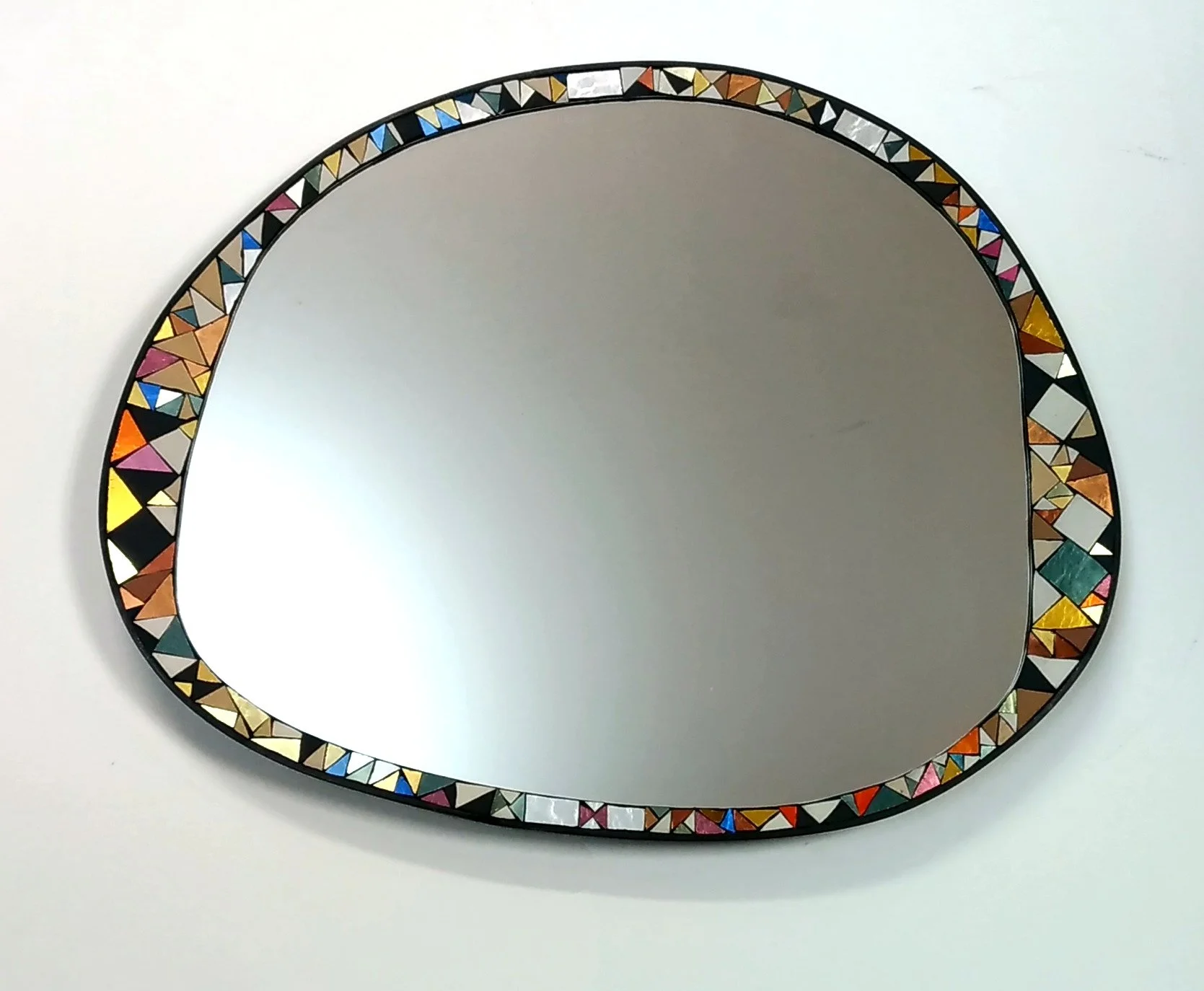 Miroir ovale en mosaïque avec cadre mosaïque colorée, posé sur fond blanc.