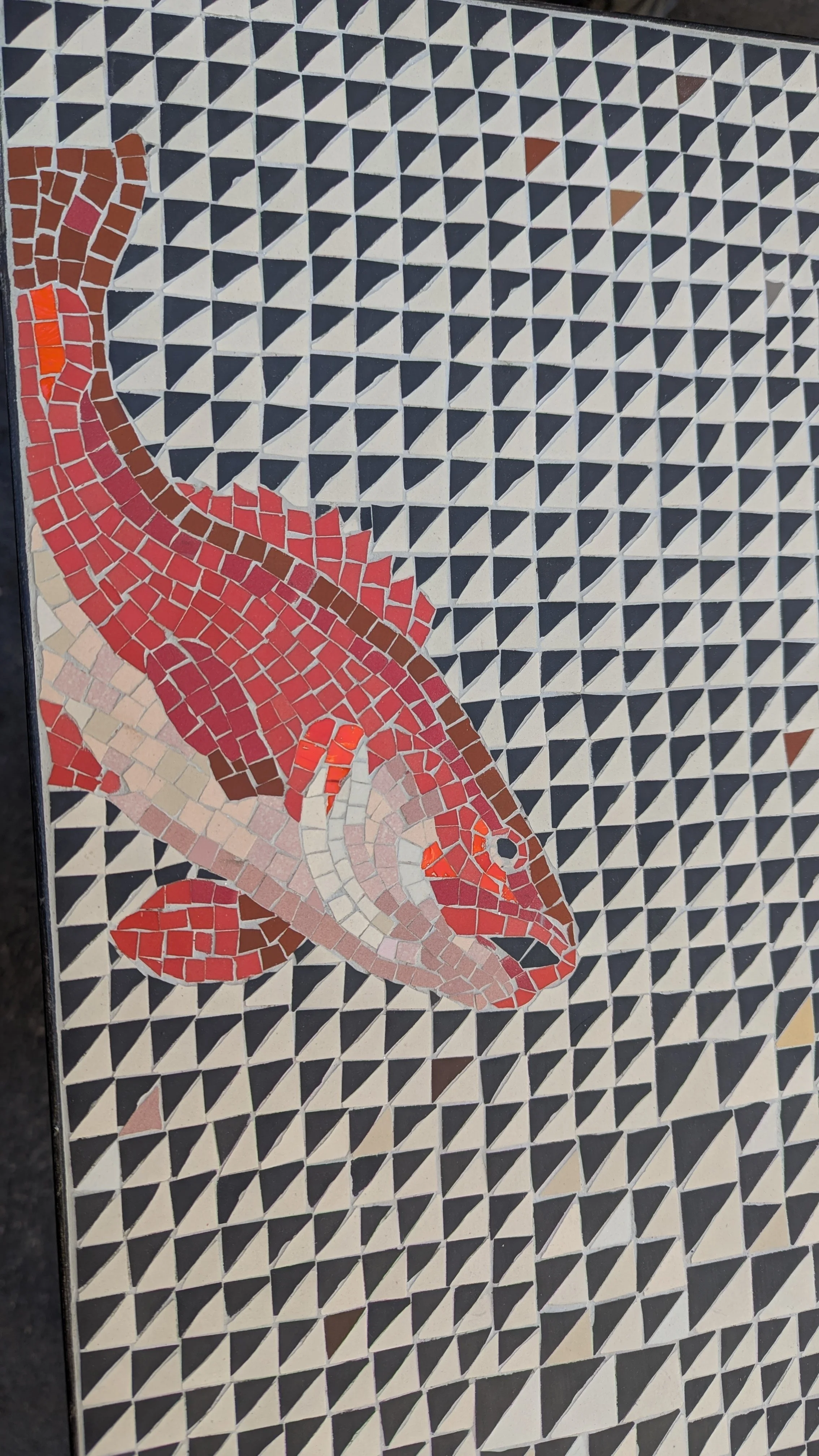 Table en mosaïque avec une représentation artistique de chameau coloré en rouge, beige, et marron sur un fond de petits triangles noirs et blancs.