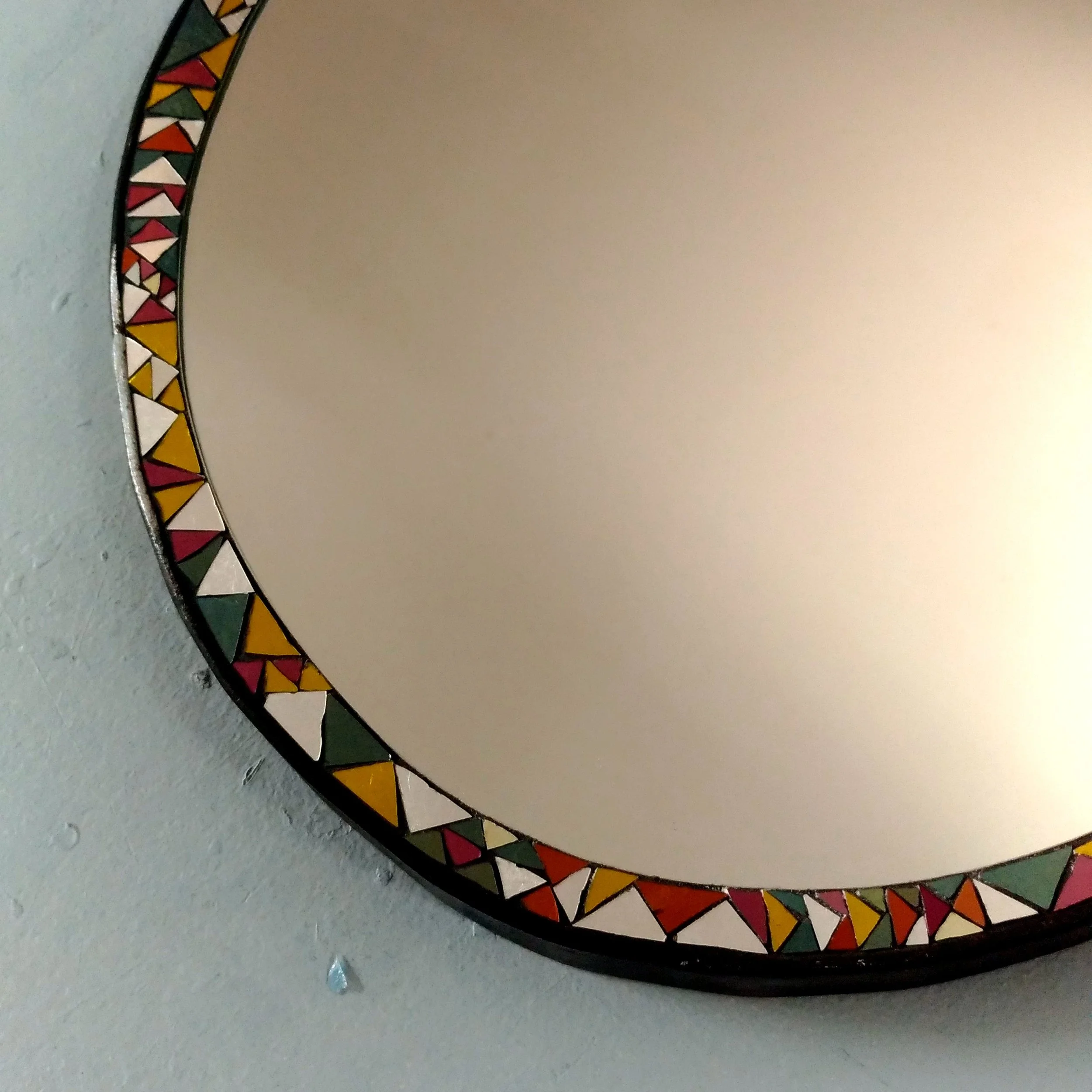 Détails d'un miroir en mosaïque, décoration multicolore avec des triangles, couleurs rouge, blanc, jaune, vert, noir.