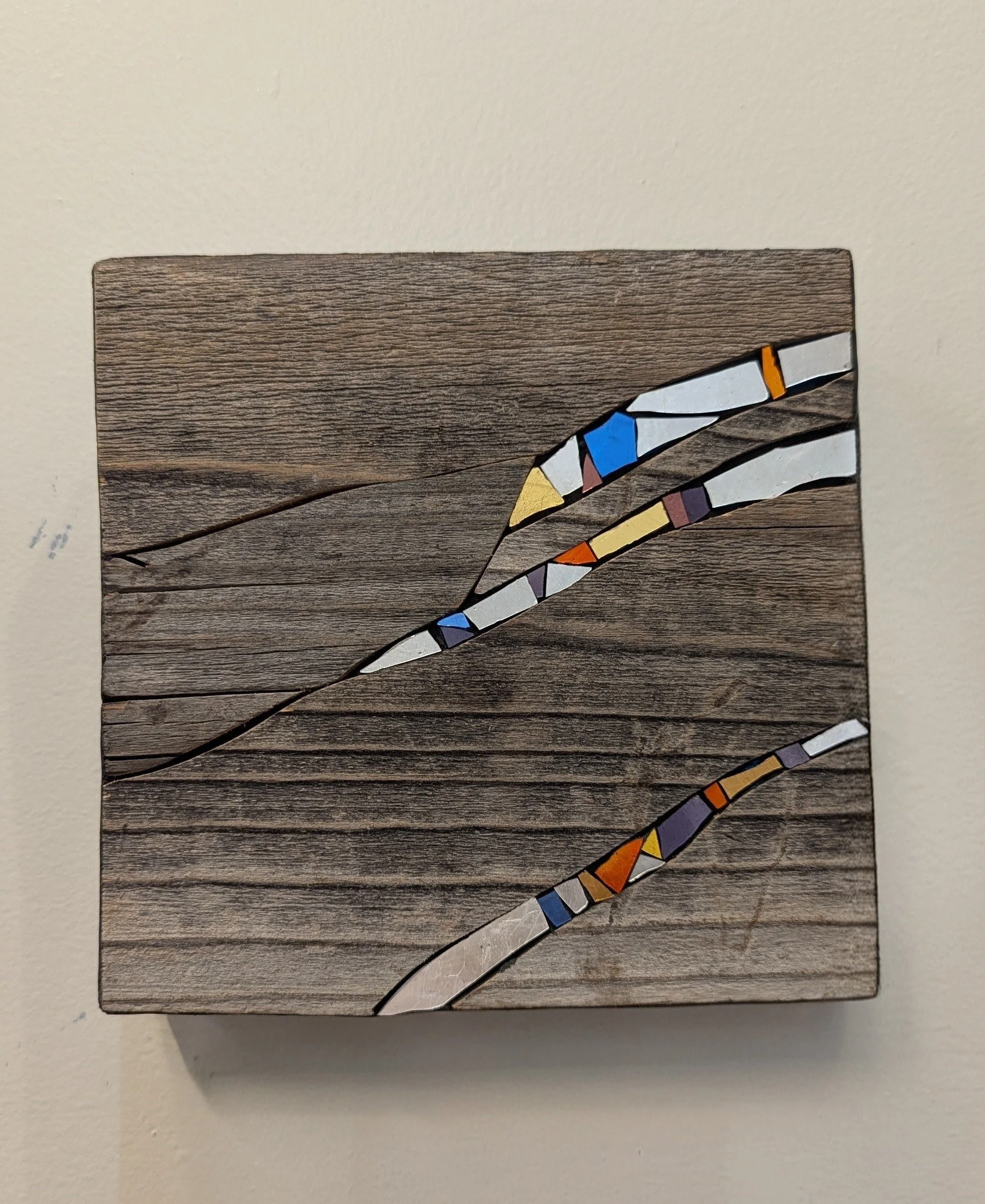 Tableau en bois avec un dessin en mosaïque colorée représenté en diagonale.