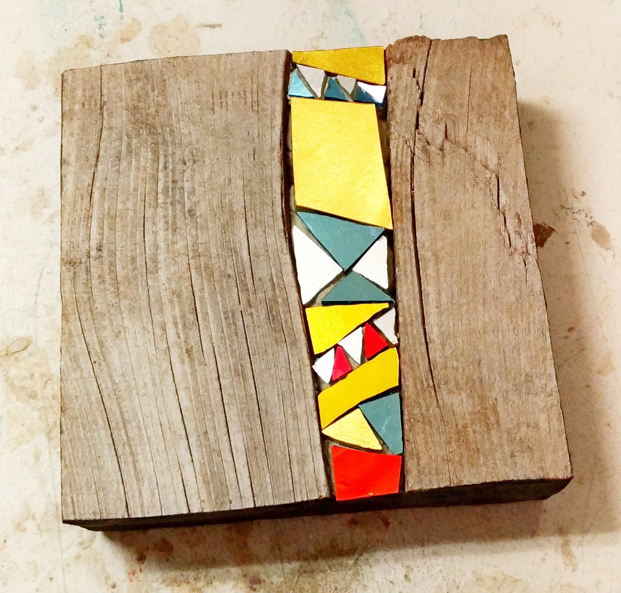 Une pièce en bois avec une rangée de petites formes en bois peintes en rouge, jaune, bleu, vert et blanc
