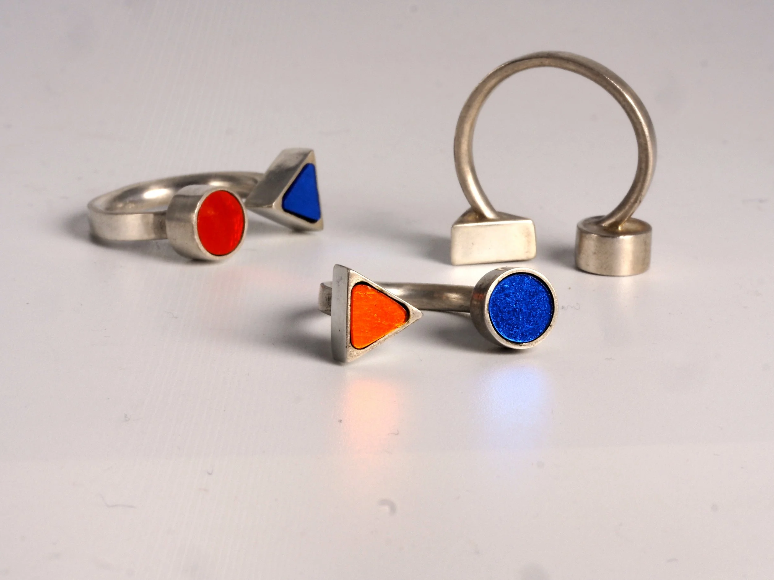 Bague en mosaïque avec des formes colorées : un triangle bleu, un cercle rouge, et un triangle orange.