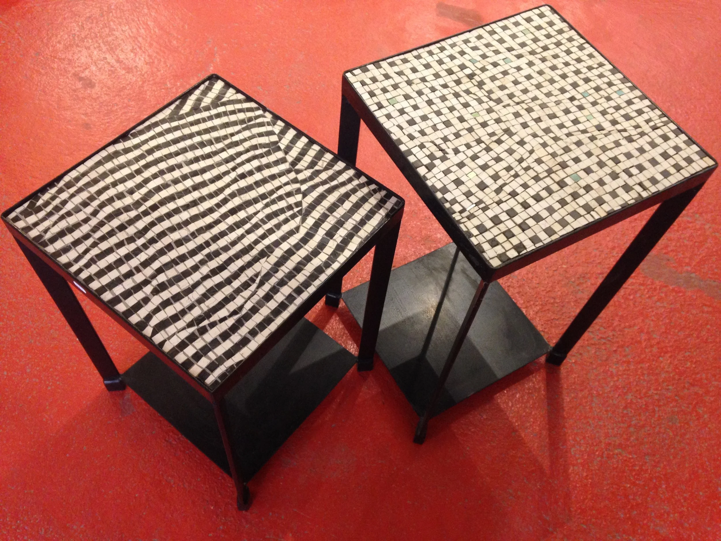 Deux tables rectangulaires avec motifs en mosaïque noire et blanche, placées sur un sol rouge