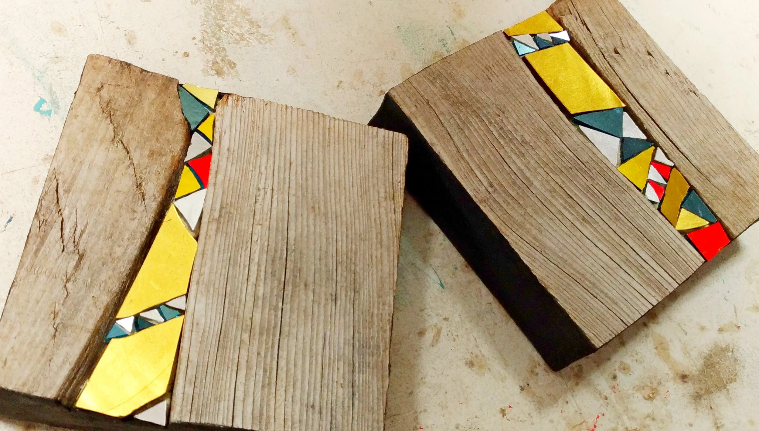 Deux morceaux de bijoux muraux en mosaïque de bois massif avec des motifs colorés peints ou collés à leurs extrémités.