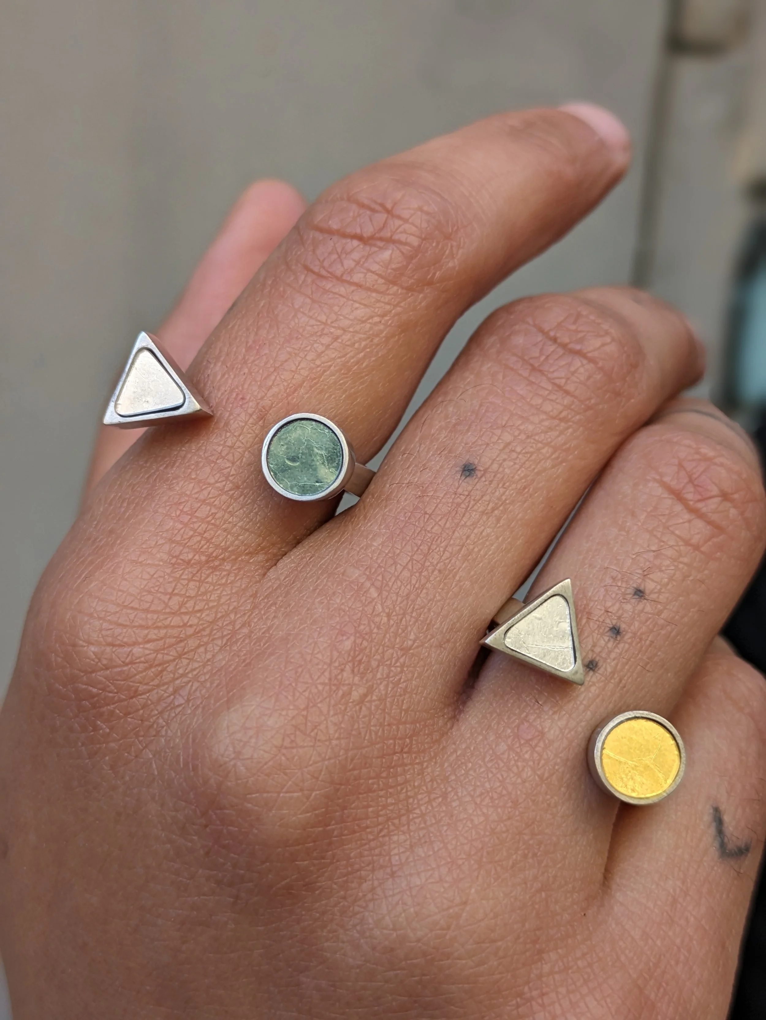 Une main portant plusieurs bagues modernes en mosaïque de différentes formes et couleurs
