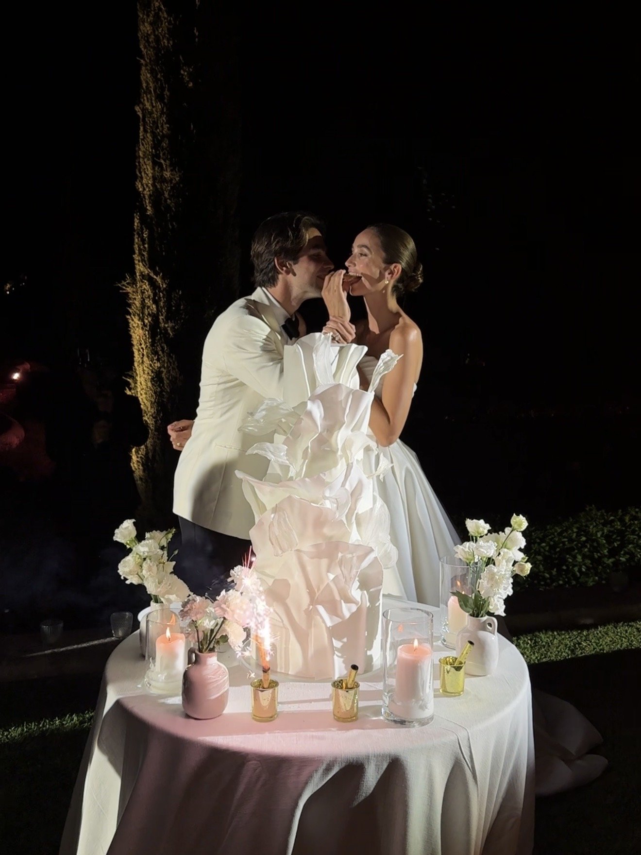 Bride and groom cutting cake at an evening wedding reception
