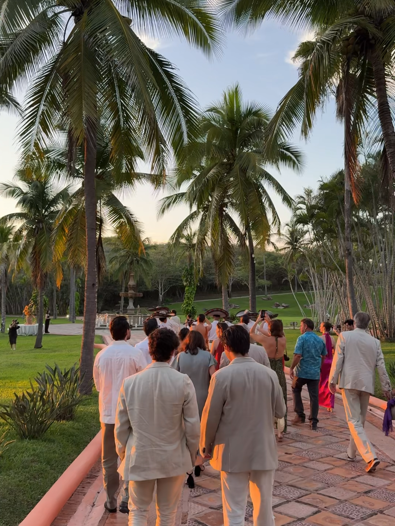 Wedding guests walking to a tropical beach wedding ceremony at sunset in Mexico
