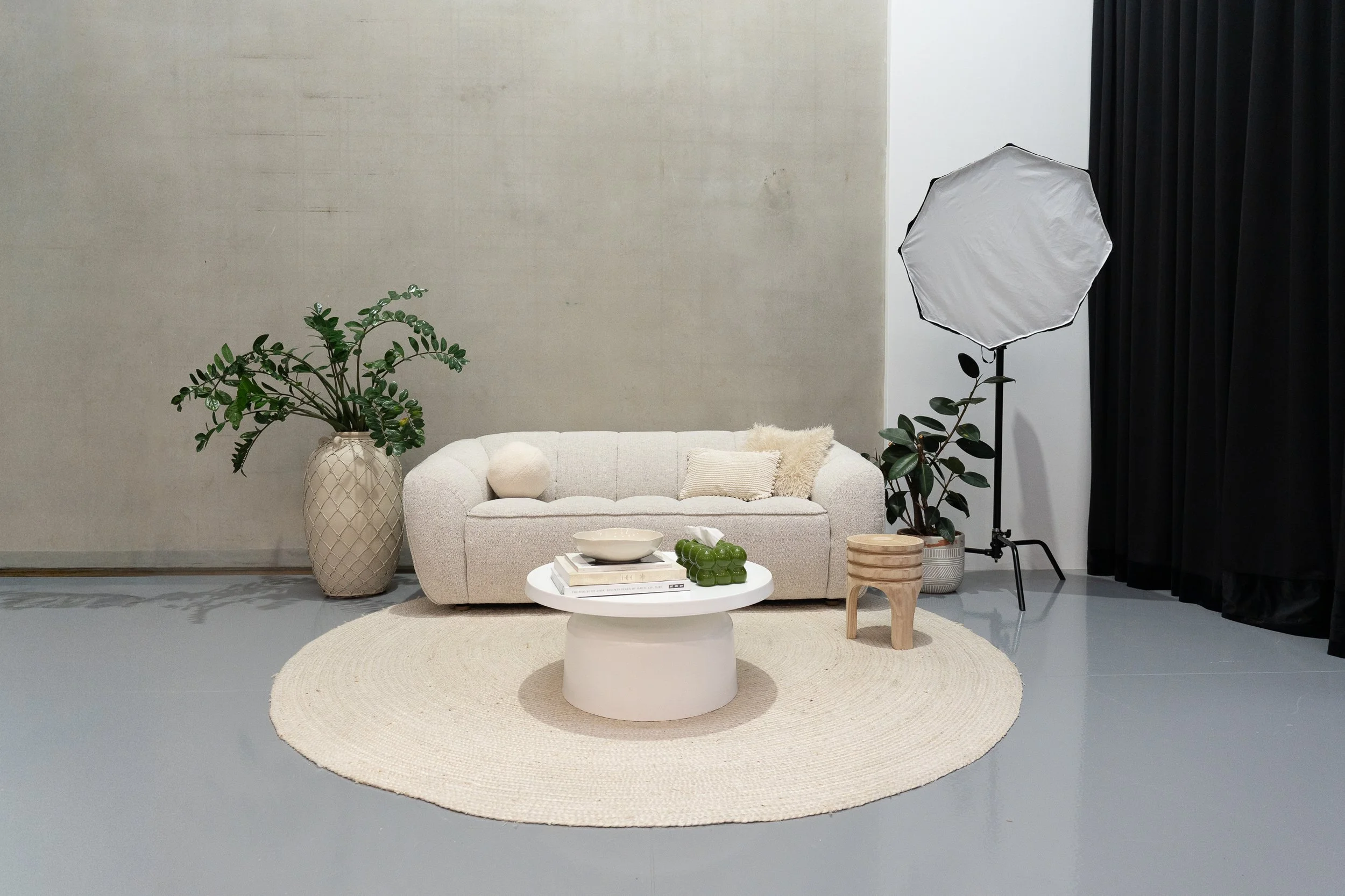 Empty room with rows of black metal chairs, a small table, and potted plants in the corner.