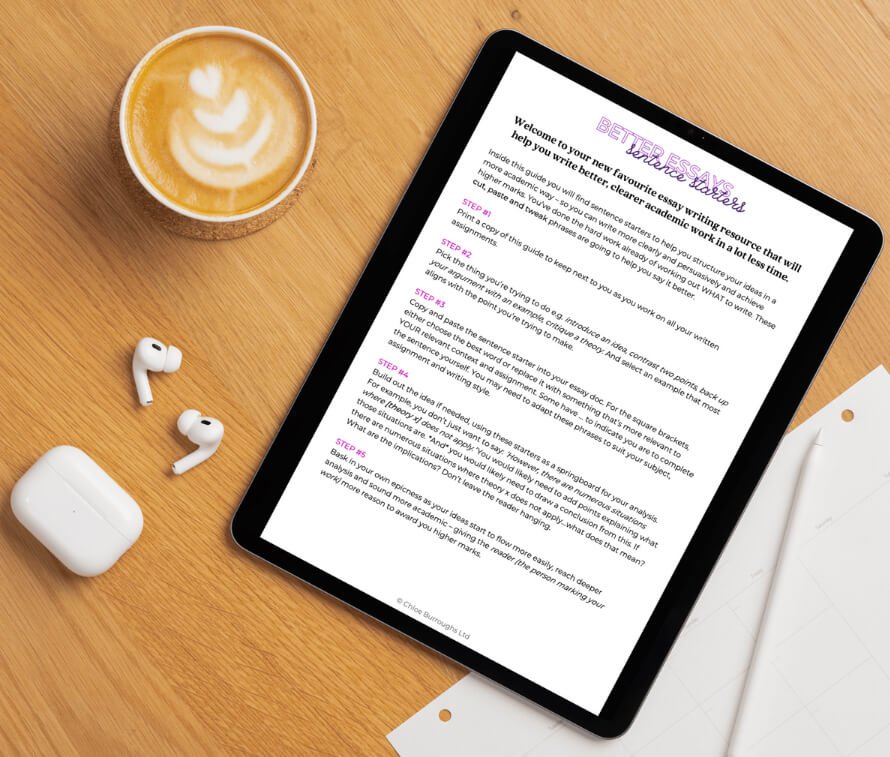 Tablet displaying a guide titled 'PETER JESSKINS' with instructions for writing essays, placed on a wooden desk next to a cup of latte with foam art, wireless earbuds, and a white notebook.