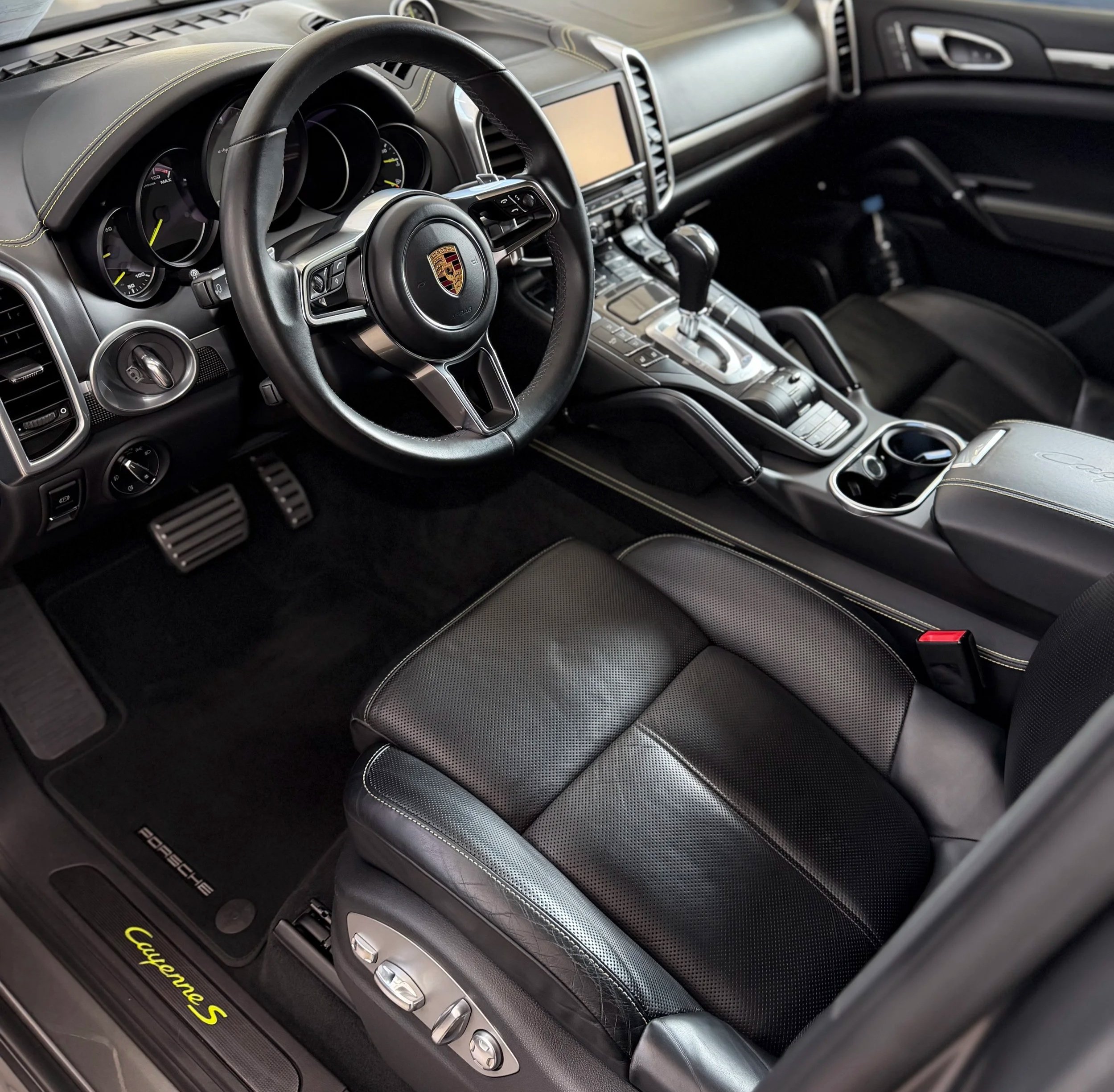 Interior of a Porsche Cayenne S showing the steering wheel, dashboard, gear shifter, and center console. Clean Interior