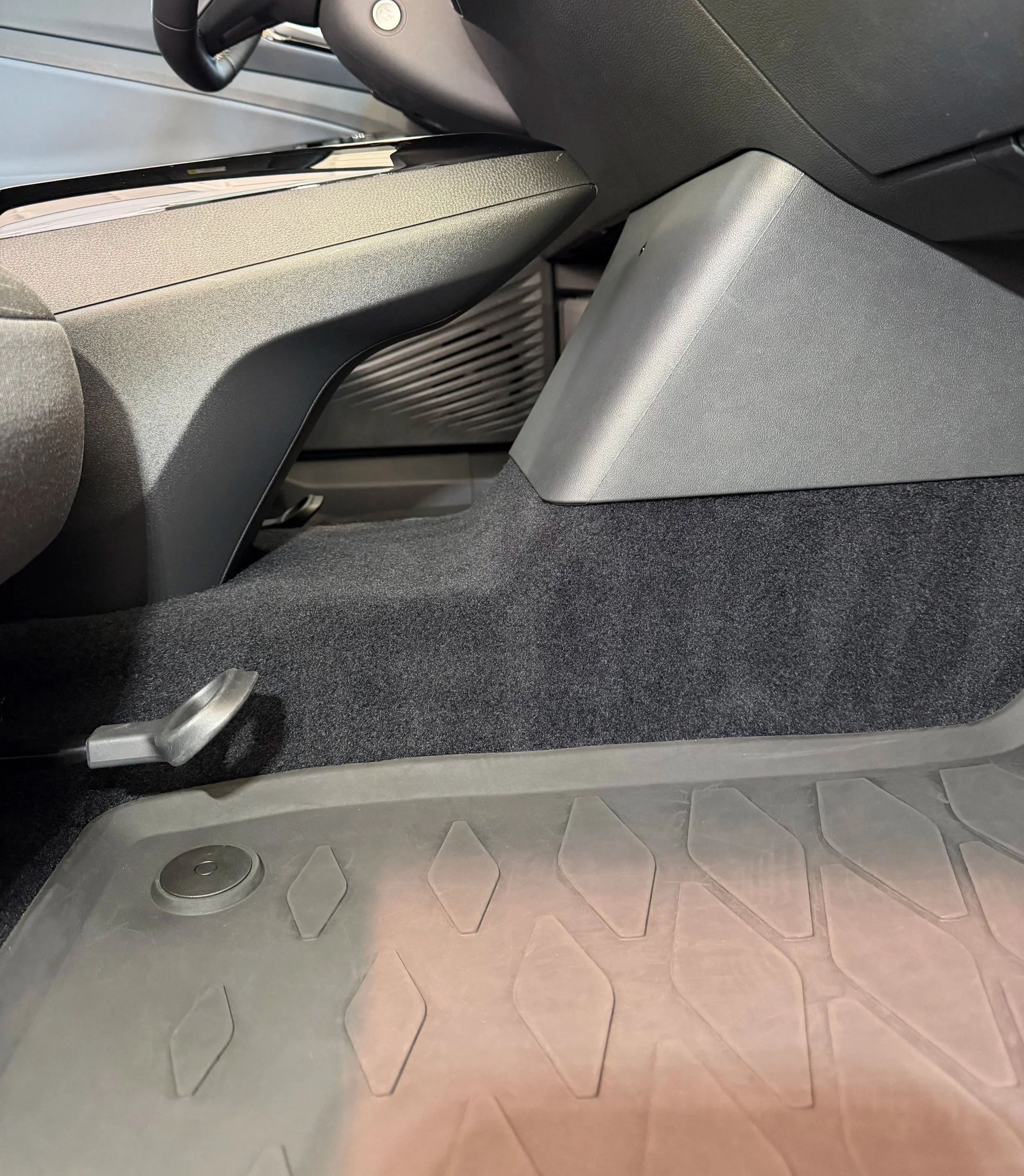 View of the floor of a modern train, showing a metal floor with hexagonal tiles, a drainage hole, and a black rubber strip near a gray partition. Cars Interior deep cleaned and pet hair removed