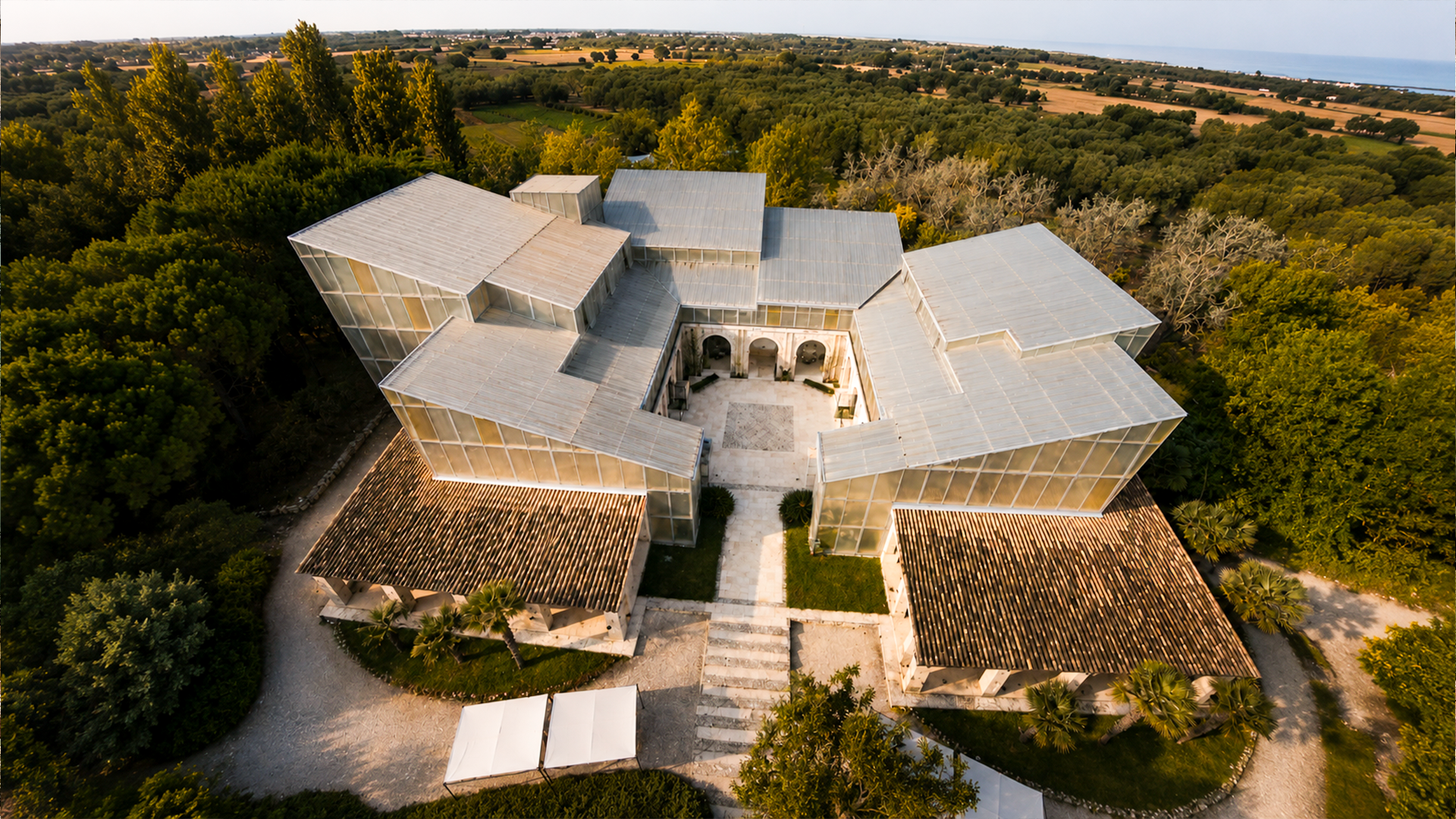 Vista aerea di un edificio moderno circondato da alberi e campi.