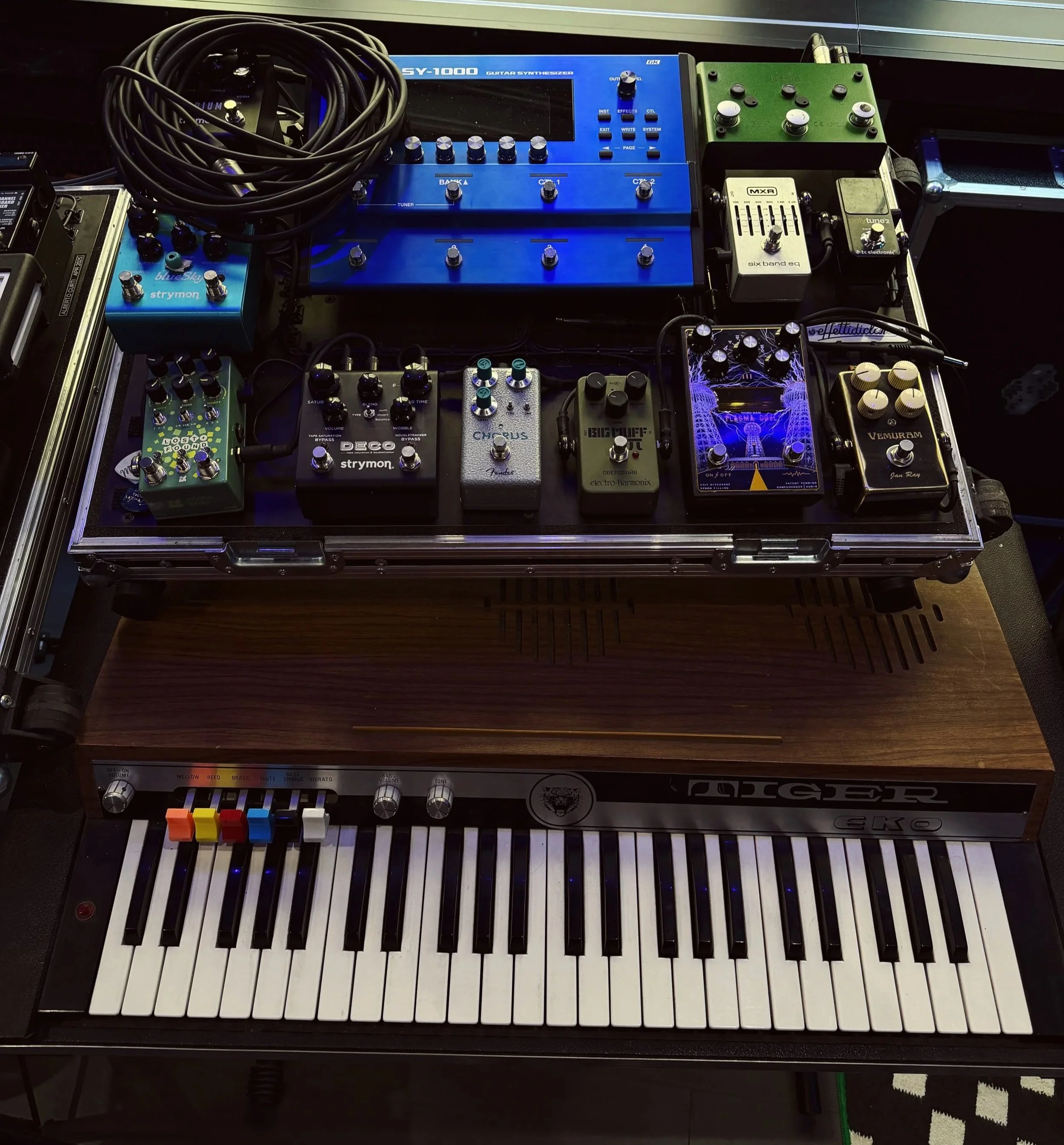 Pedaliera e strumenti musicali elettronici su un tavolo, tra cui un sintetizzatore, pedali effetti e una tastiera