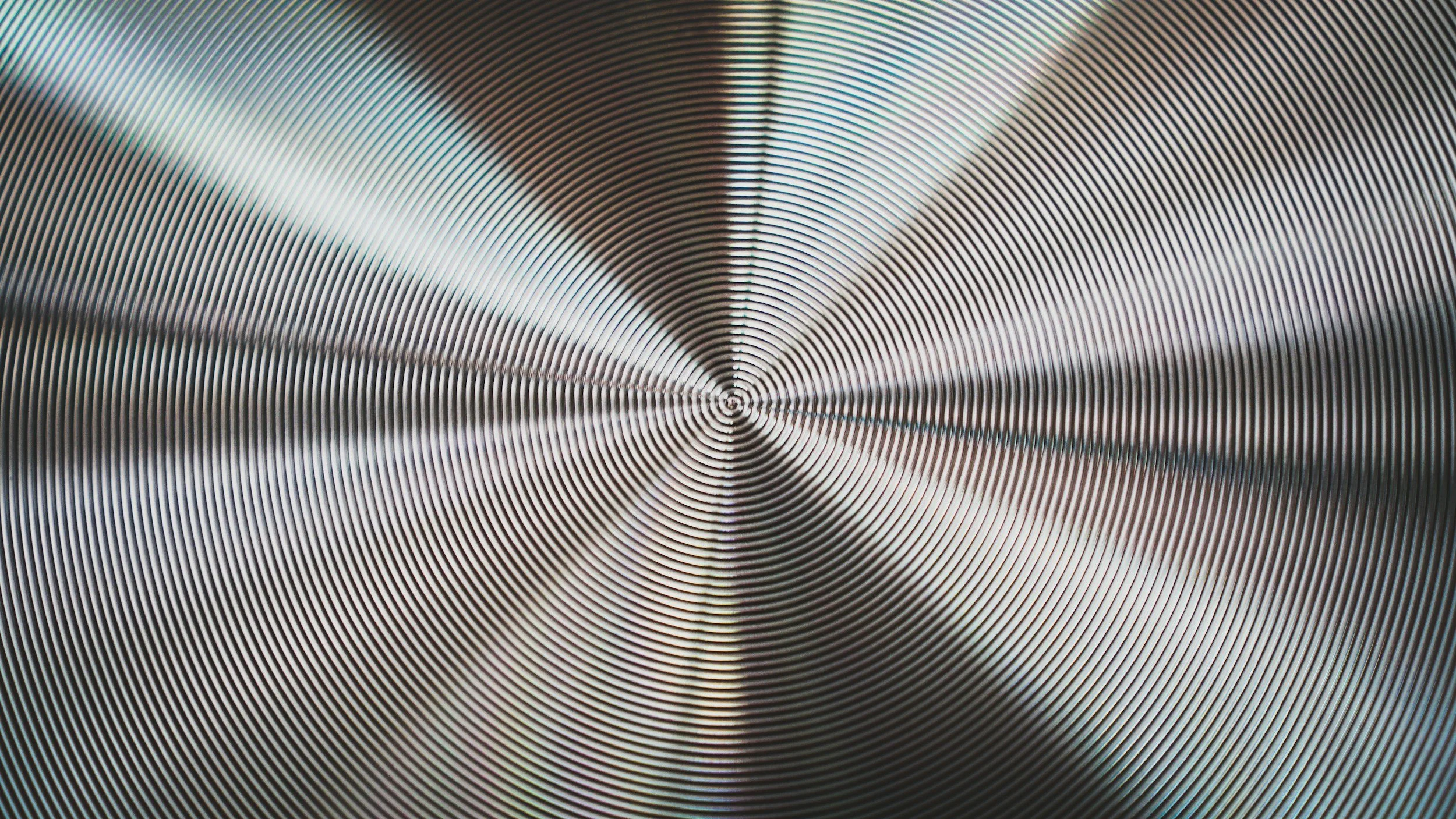 Close-up of a circular metallic grill or vent with concentric rings and lines radiating from the center.