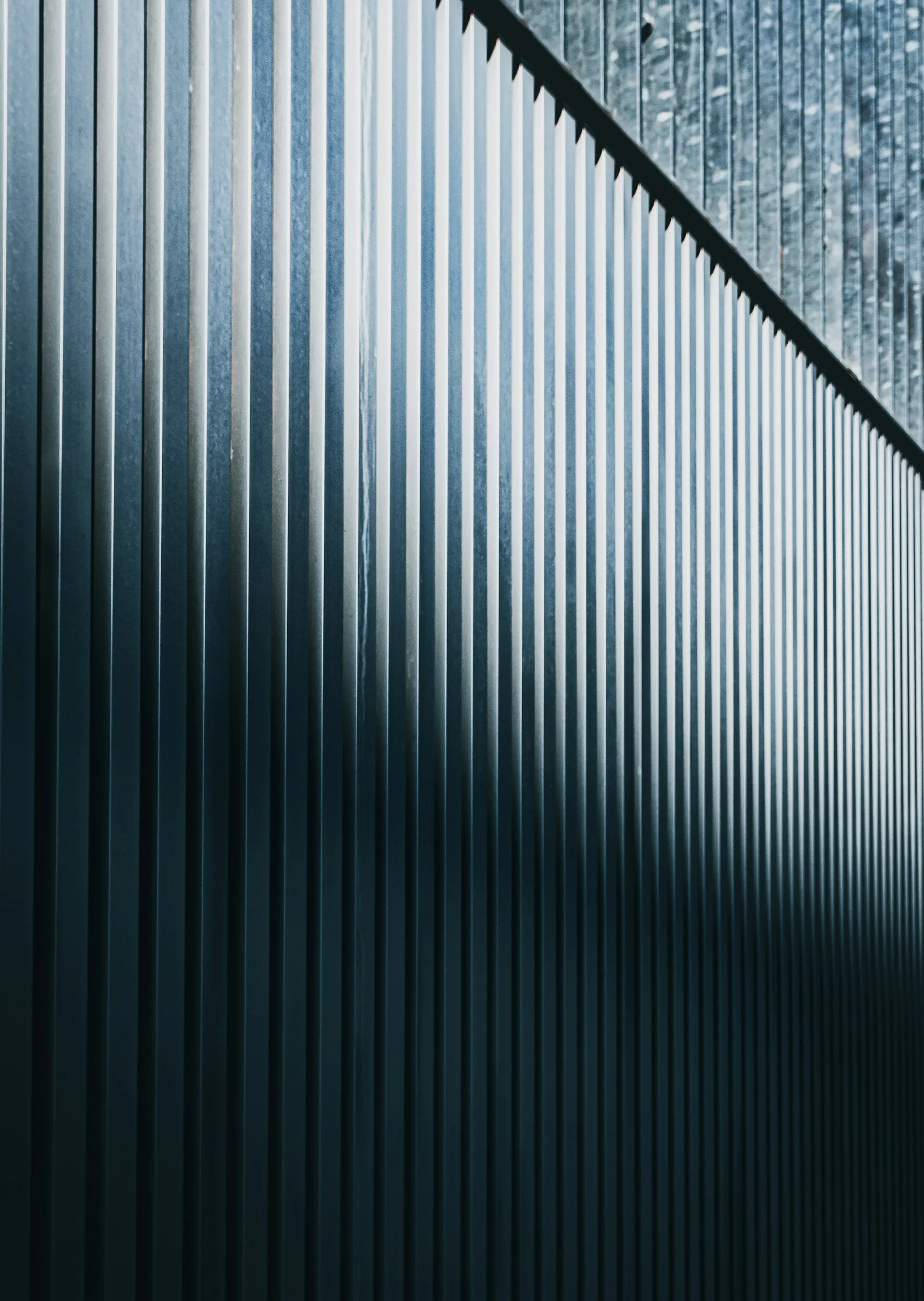 Close-up of vertical metallic slats forming a geometric pattern, with contrasting shades of gray and silver.