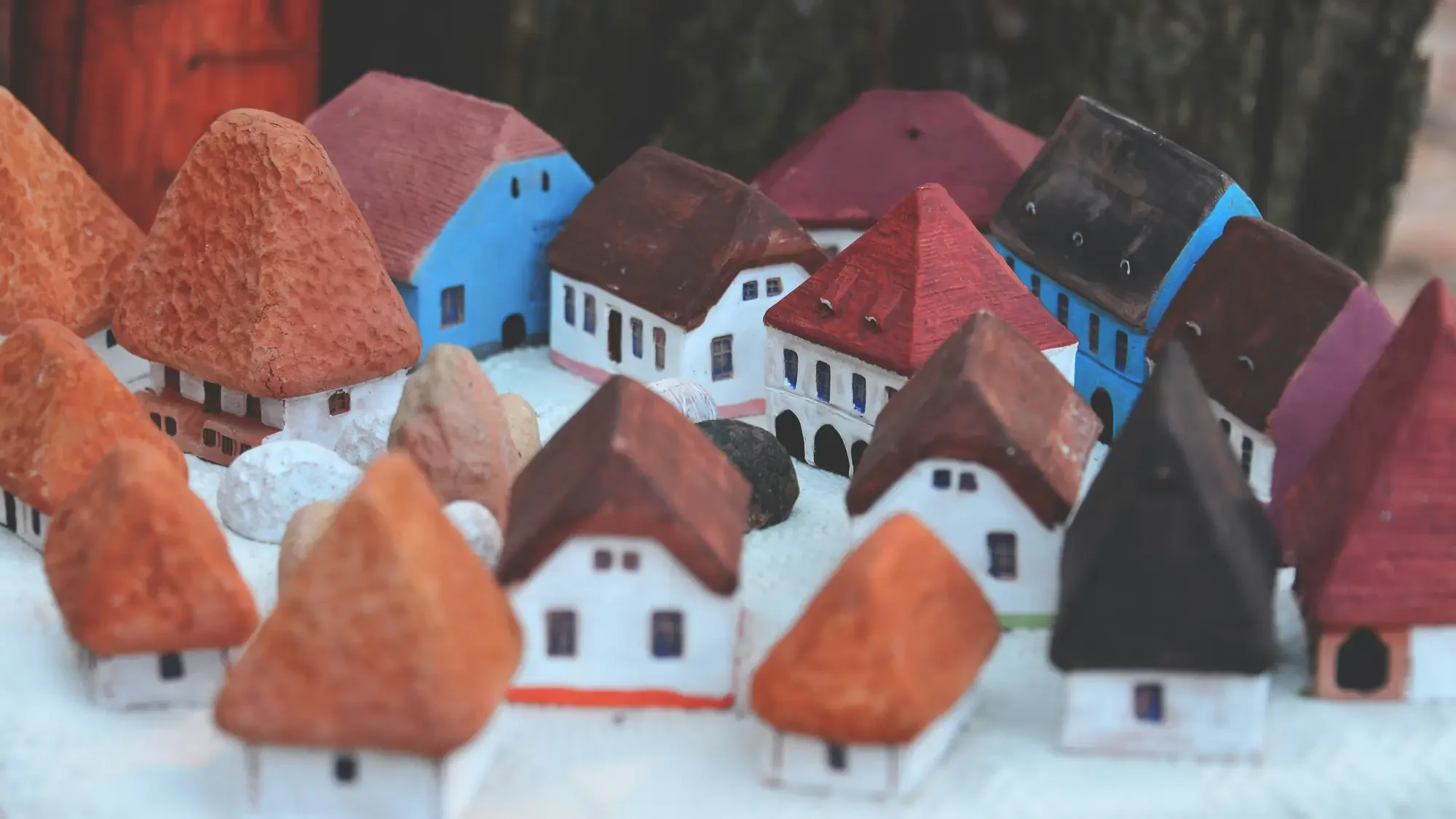 Miniature model of a village with small colorful houses and orange, red, black, and white rooftops.