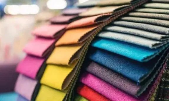 Stack of folded fabric swatches in various colors like pink, yellow, green, blue, purple, and red.