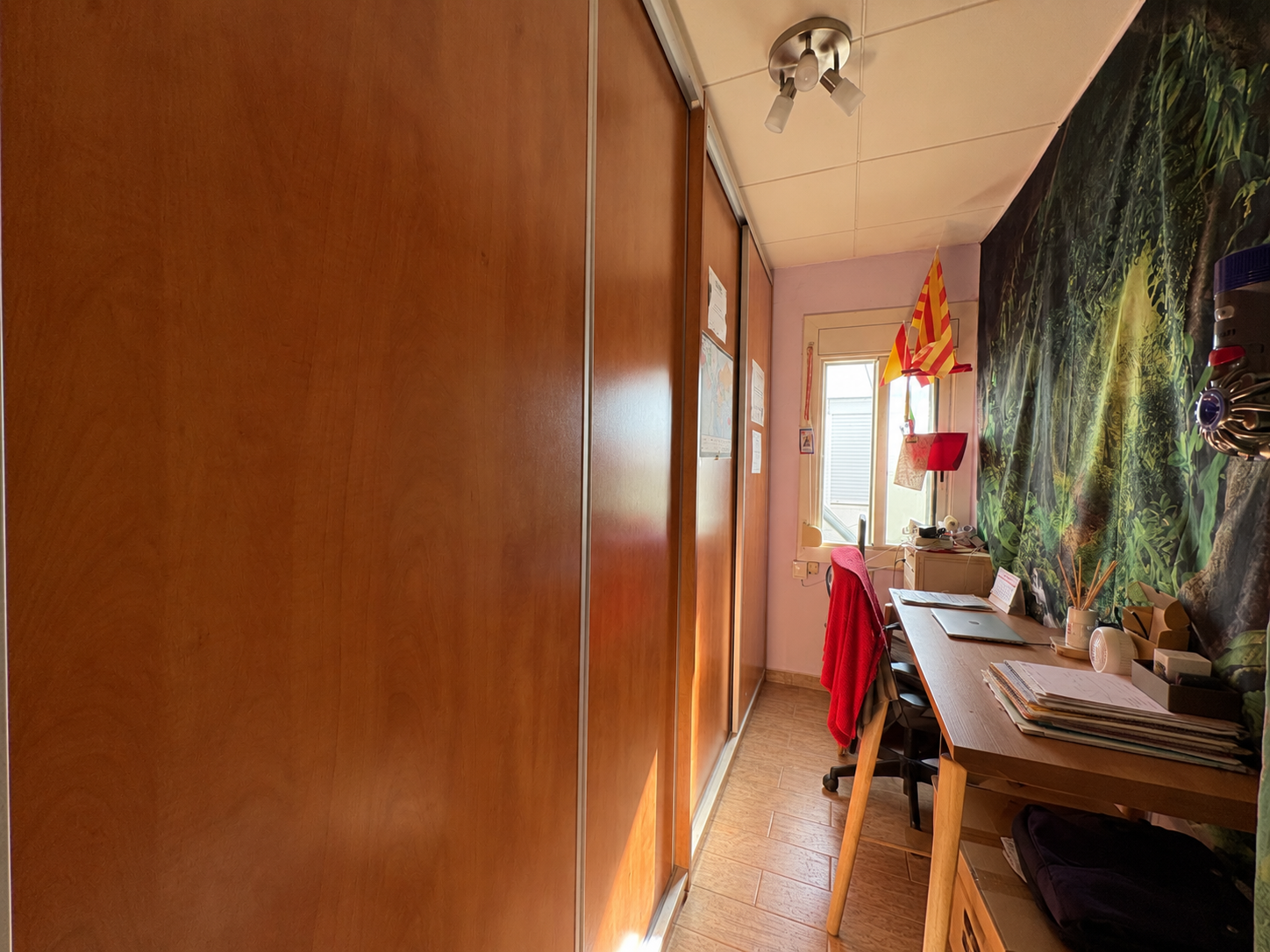 Estudio estrecho con mural selvático y armario de madera.png