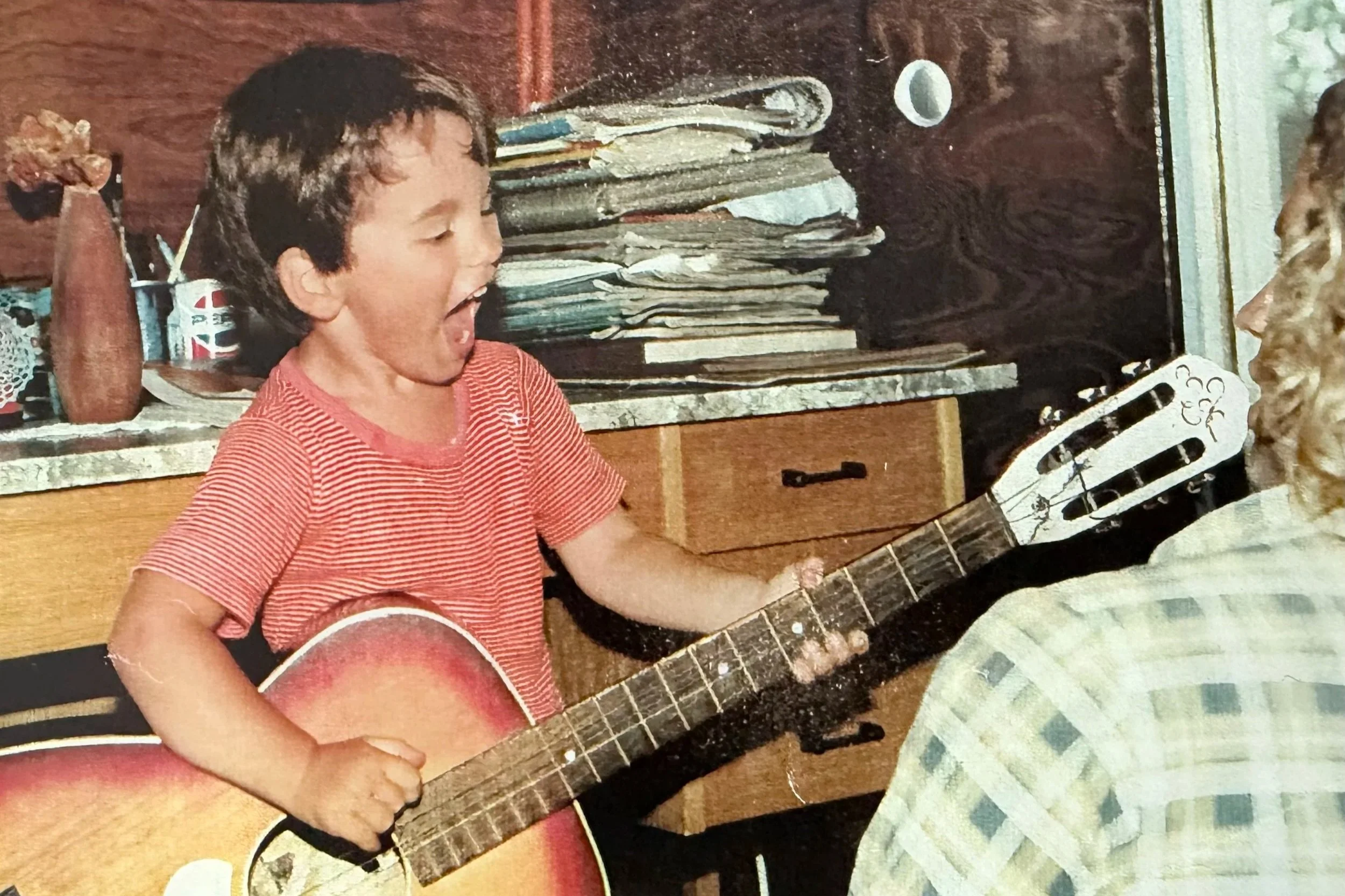 Marko Jovanović als Kind, lachend mit Gitarre.