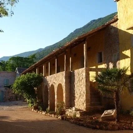 Hotel Balatura in Kroatien: altes Steinhaus mit Holzveranda vor den Bergen