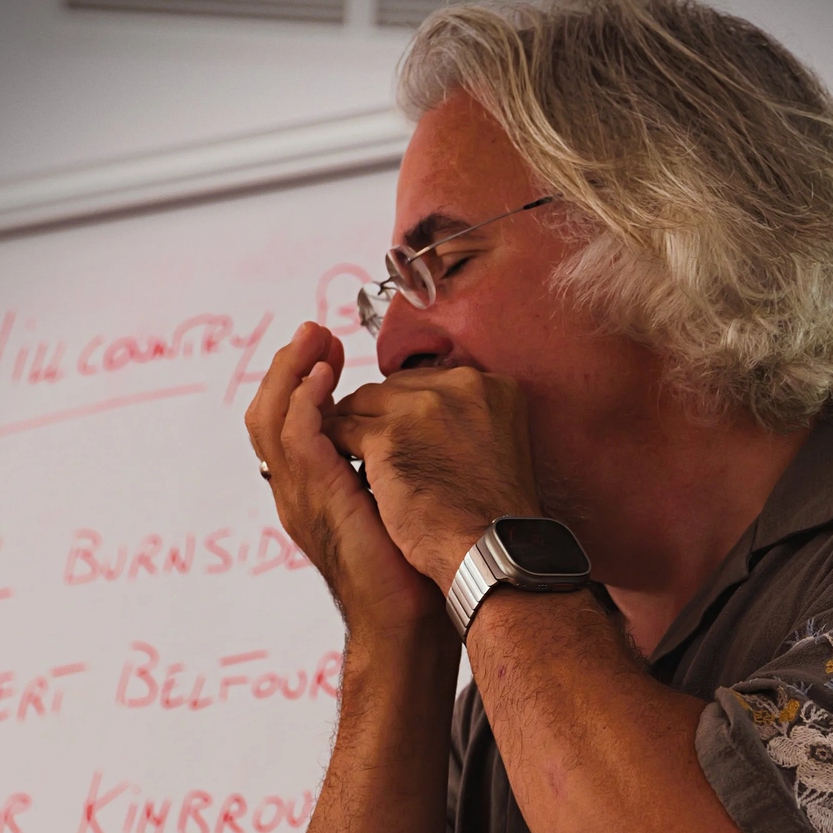 Workshop-Teilnehmer spielt Mundharmonika vor einer Tafel mit Notizen.