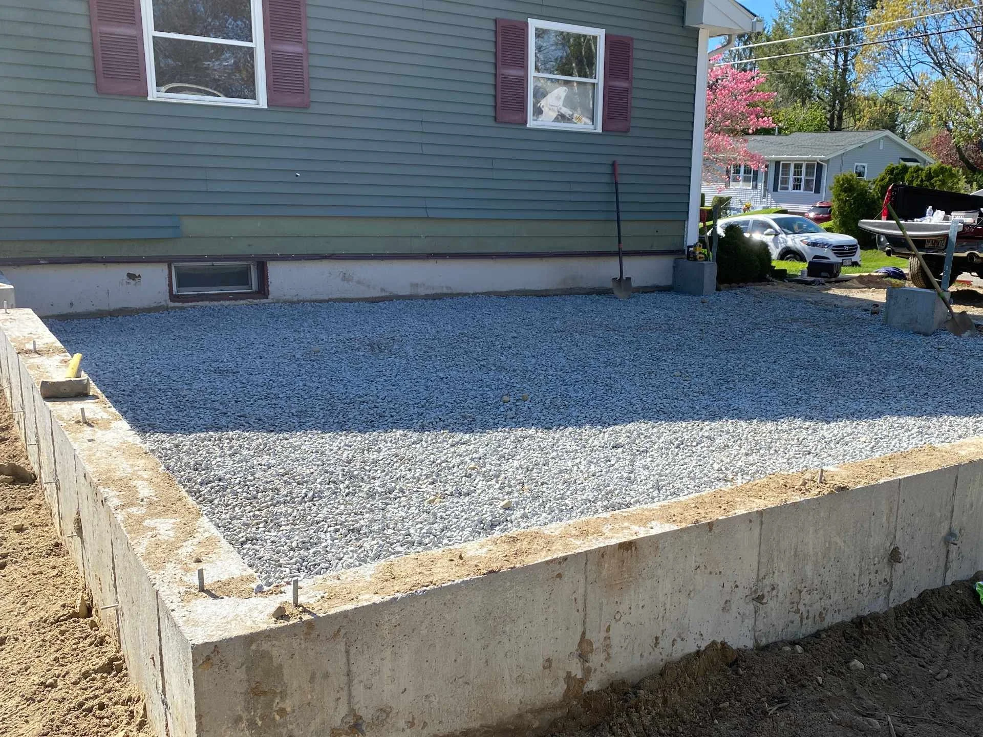A freshly built concrete foundation surrounded by gravel for a house extension under construction.