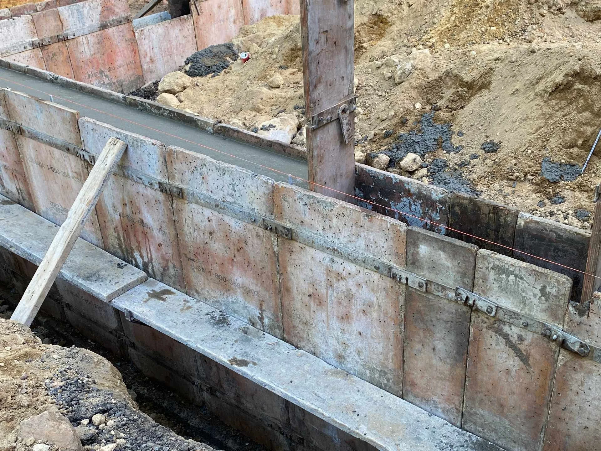 Construction site with concrete formwork and dirt, rocks, and construction materials inside
