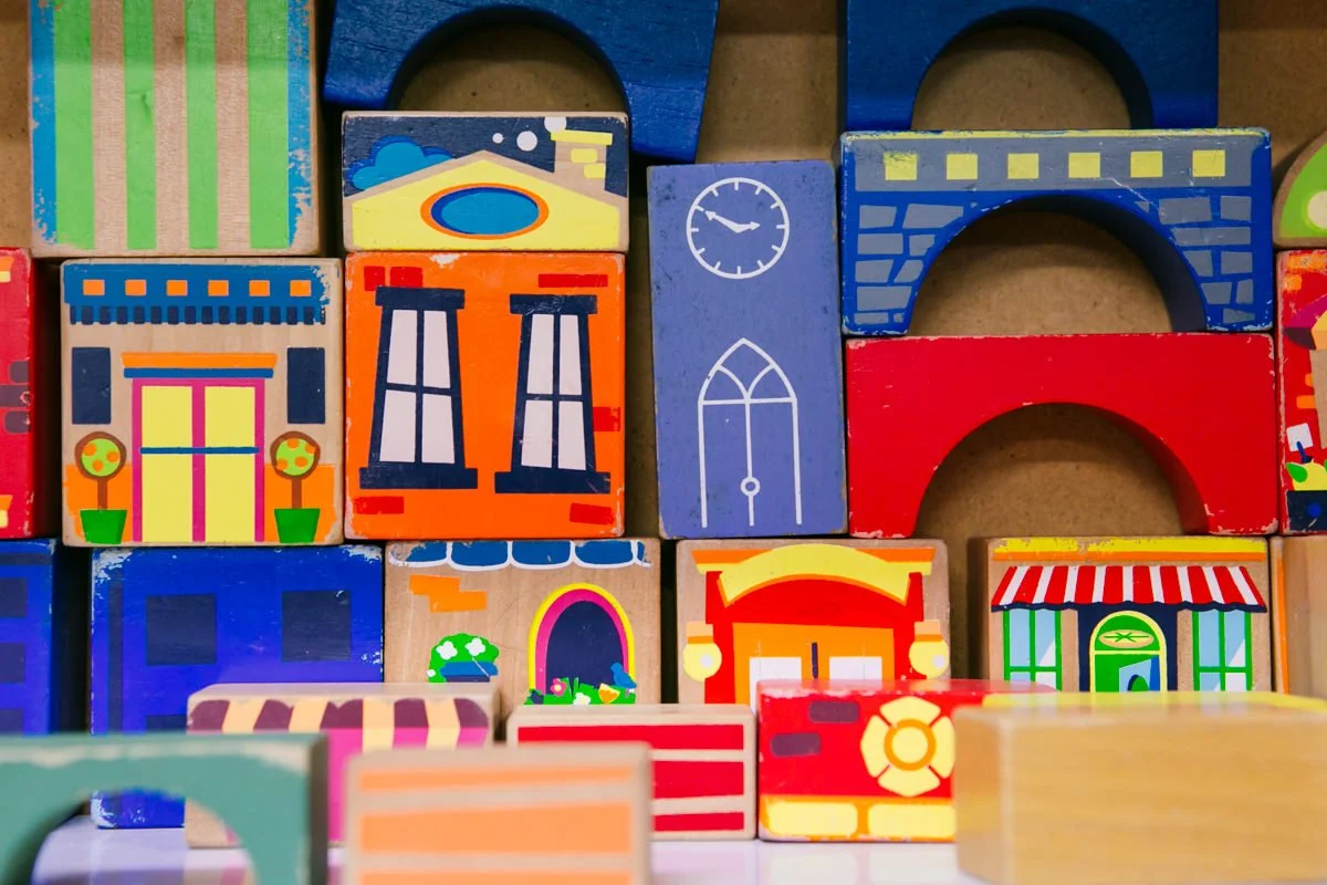 Colorful wooden toy blocks decorated with drawings of houses, windows, and doors, stacked together.