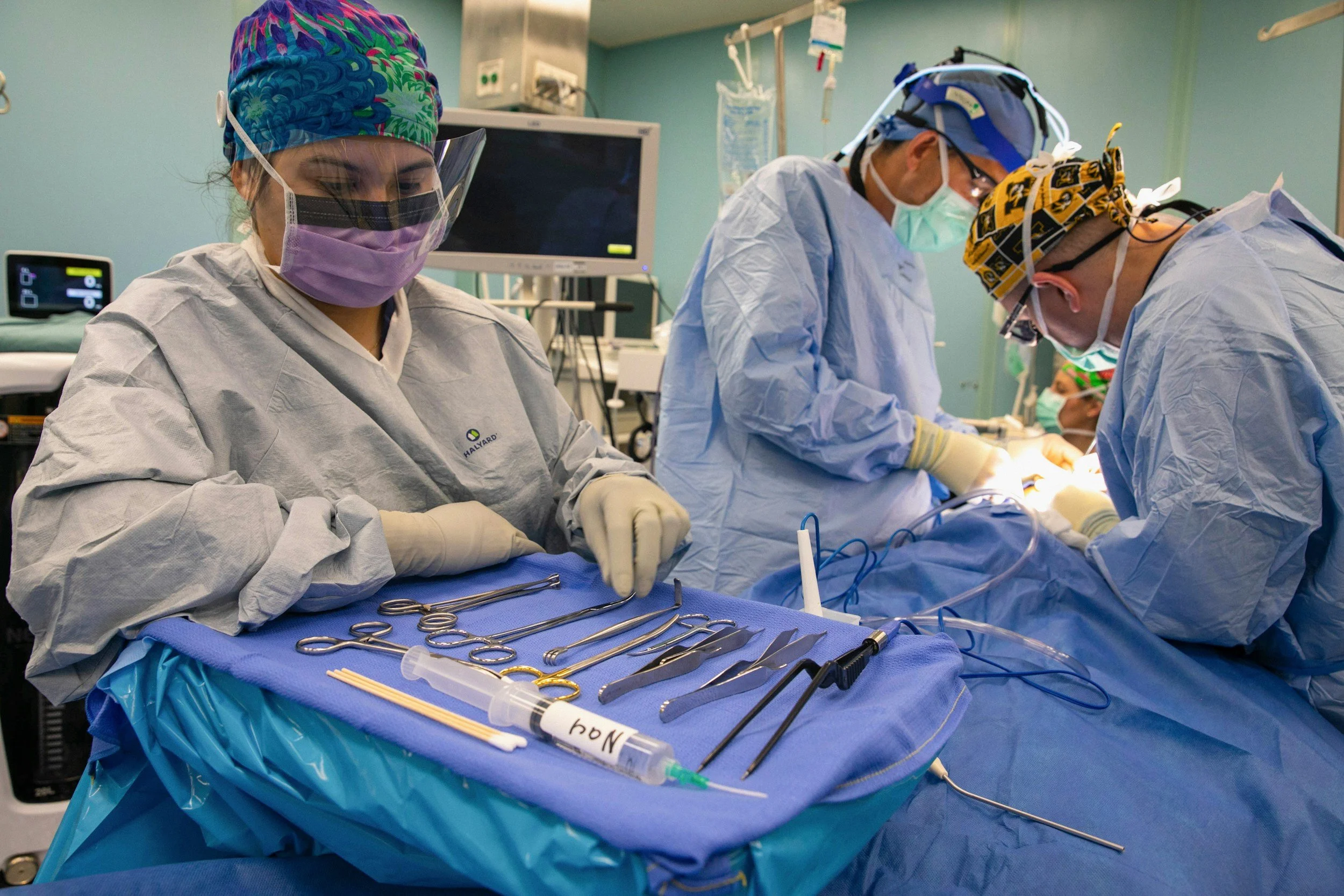 Medical team performing surgery in an operating room with surgical instruments and equipment on a sterile table.