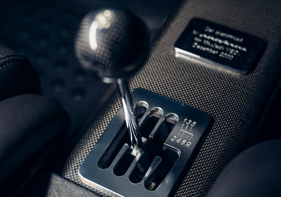 Close-up of a manual gear shift lever in a car with a textured pattern surround and a small plaque.