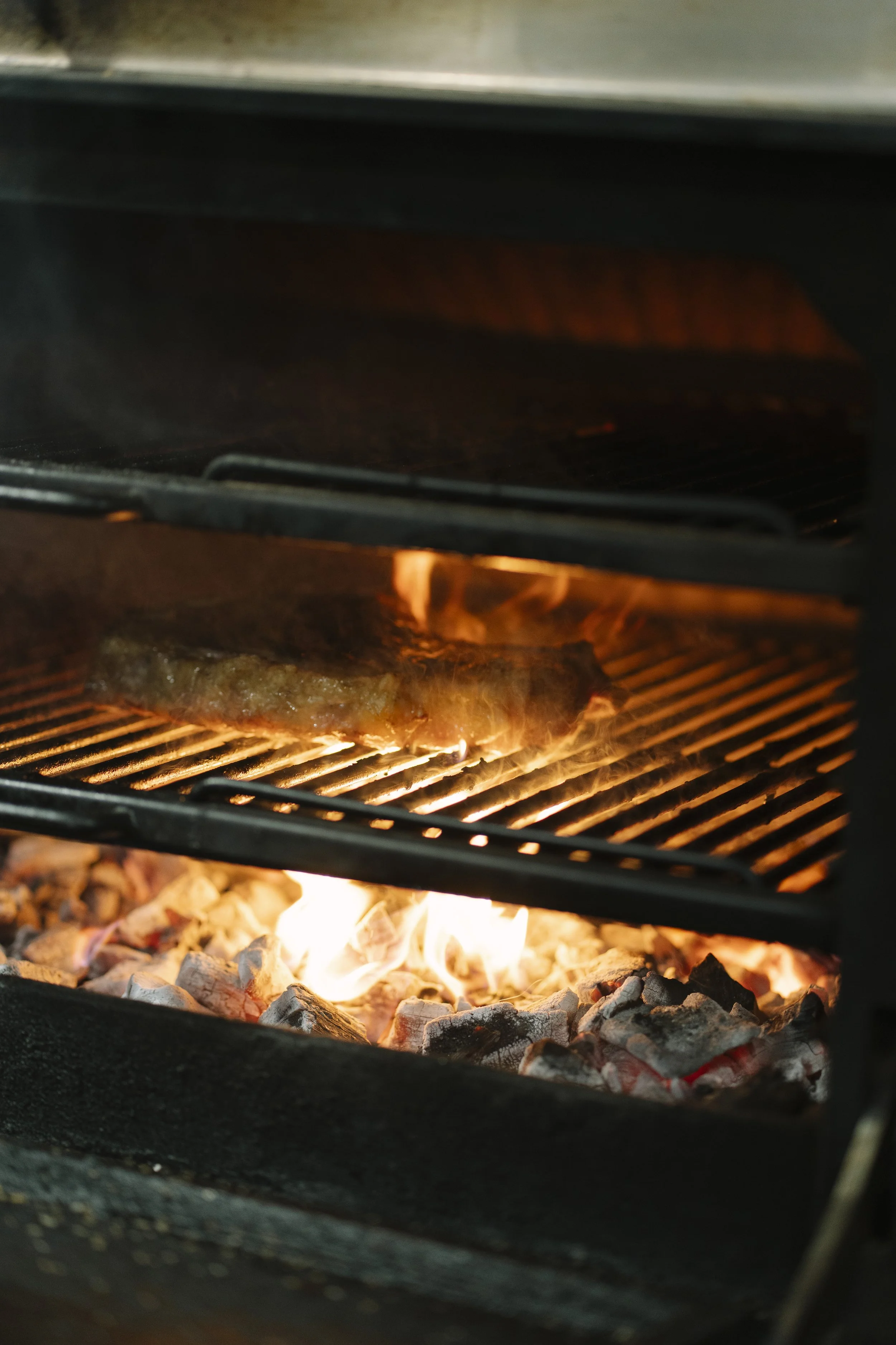 Carne premium cocinándose a la brasa sobre fuego de carbón en LAVAKA Steak House, Figueres.