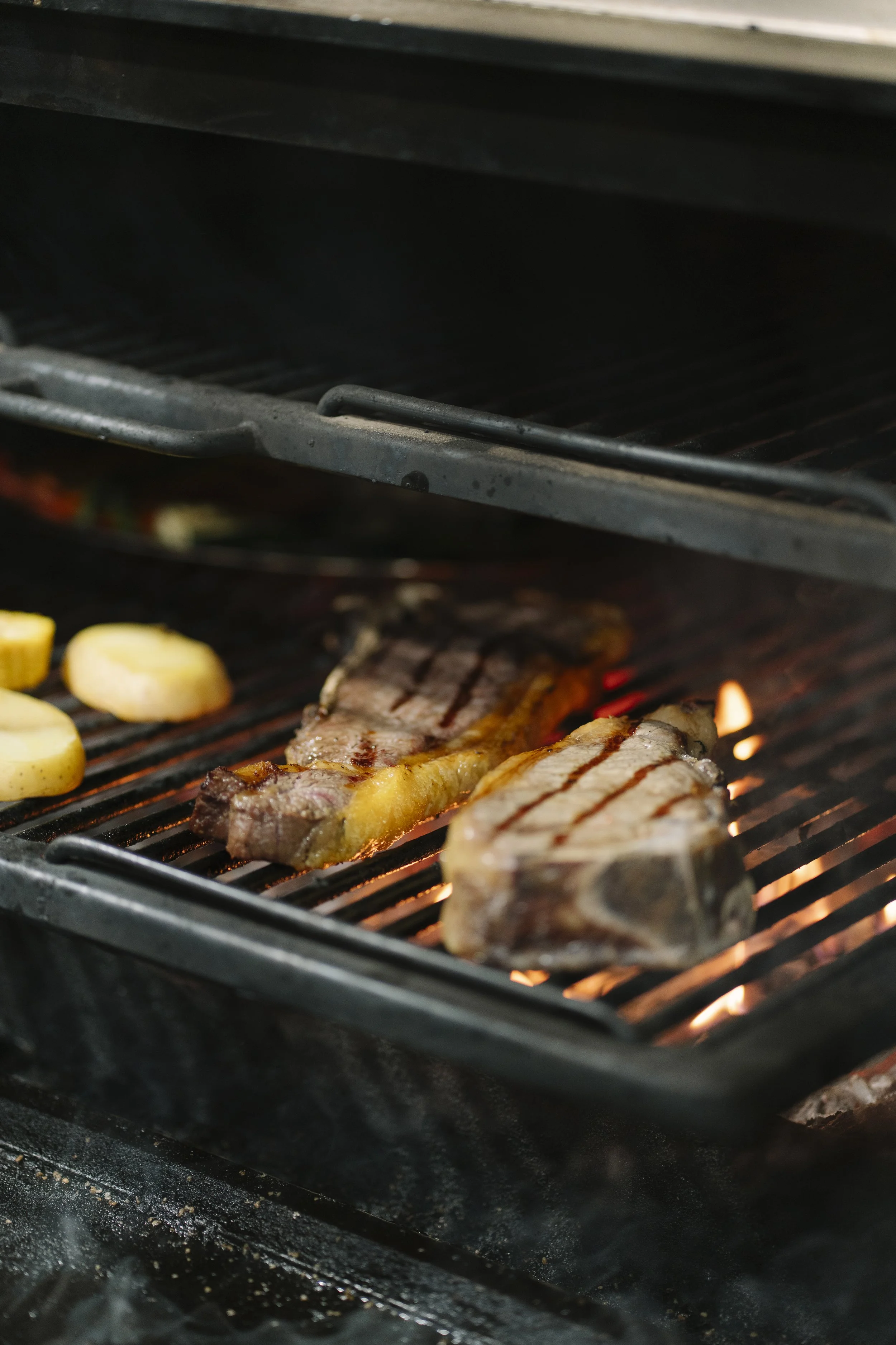 Carne premium cocinándose a la brasa sobre fuego de carbón en LAVAKA Steak House.