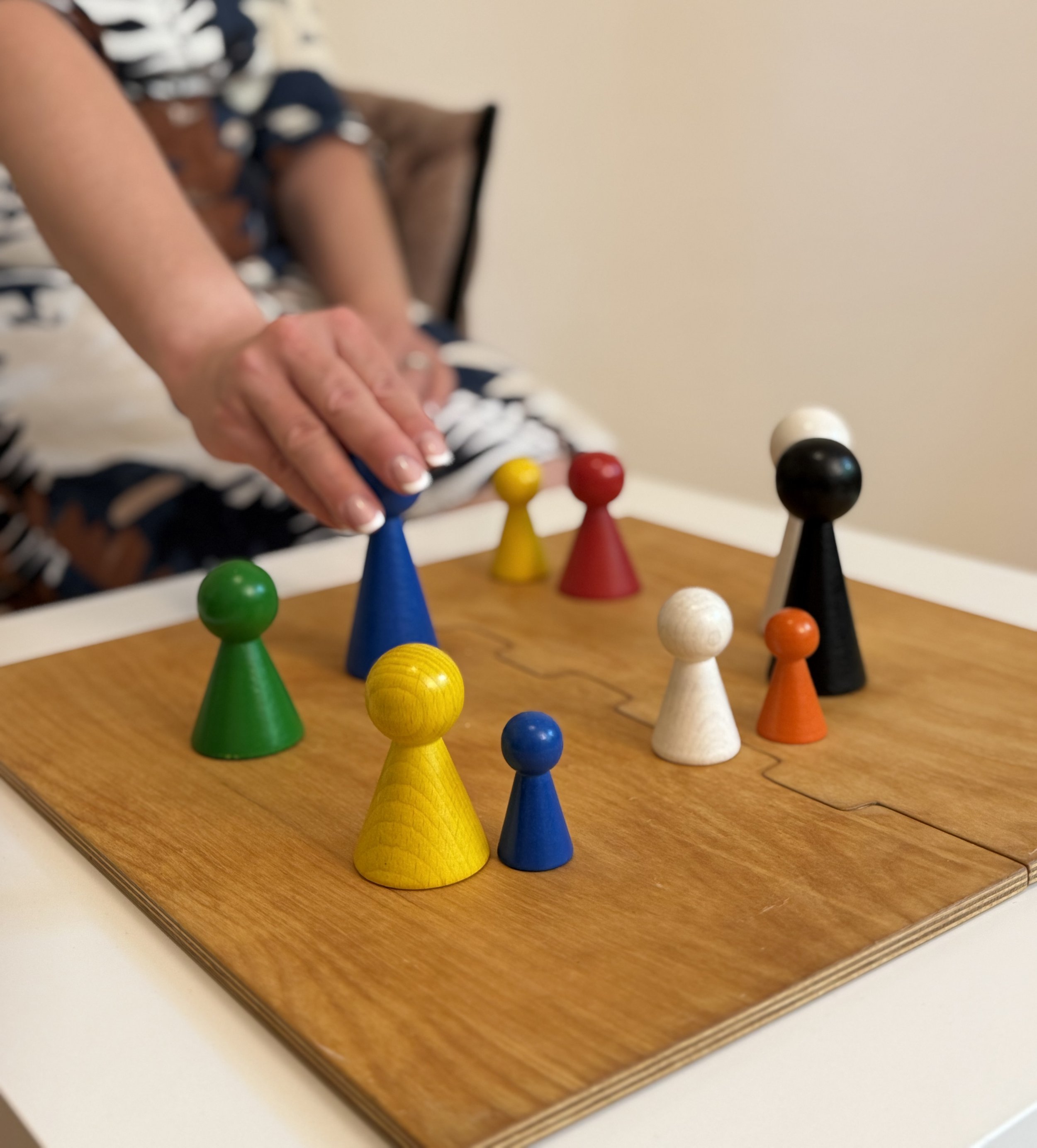 Buntes Figuren auf einem Holzbrett, darunter der Rand eines weißen Tisches.