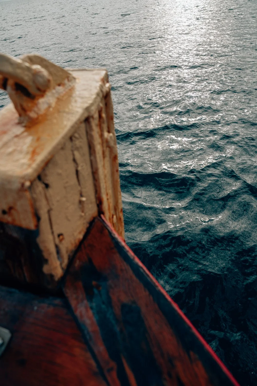 Nahaufnahme eines alten, rostigen Haken auf einem Boot, mit Blick auf das Meer im Hintergrund.