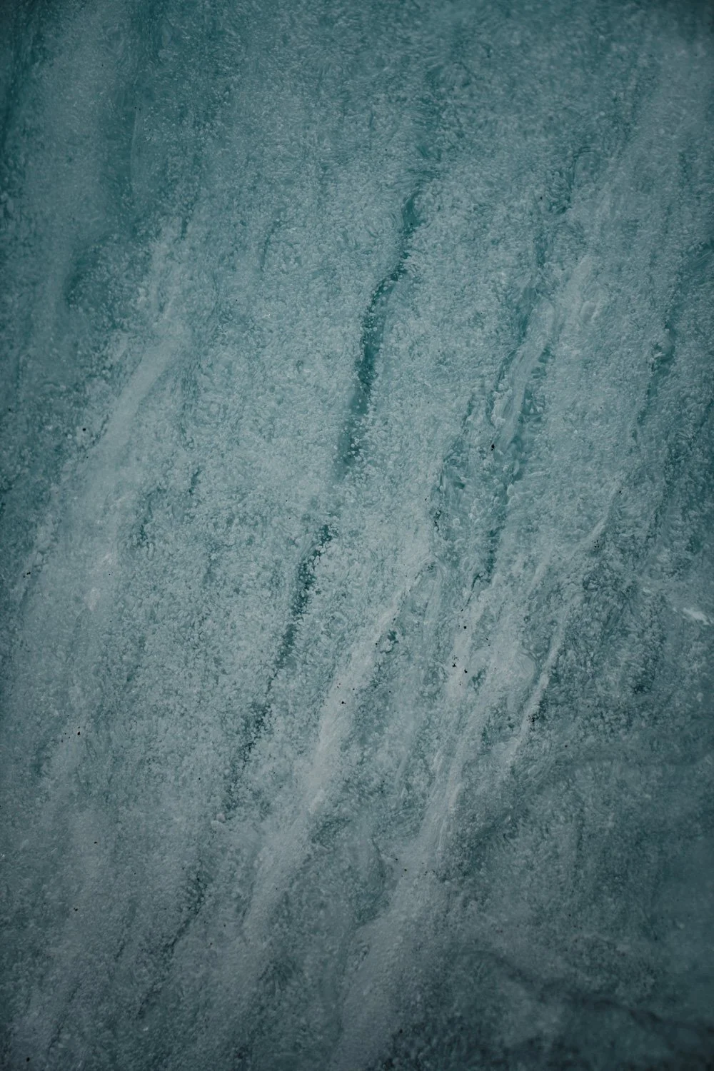 Eisschicht mit Rissen und Schneeflocken an einer Fenster- oder Glasfläche