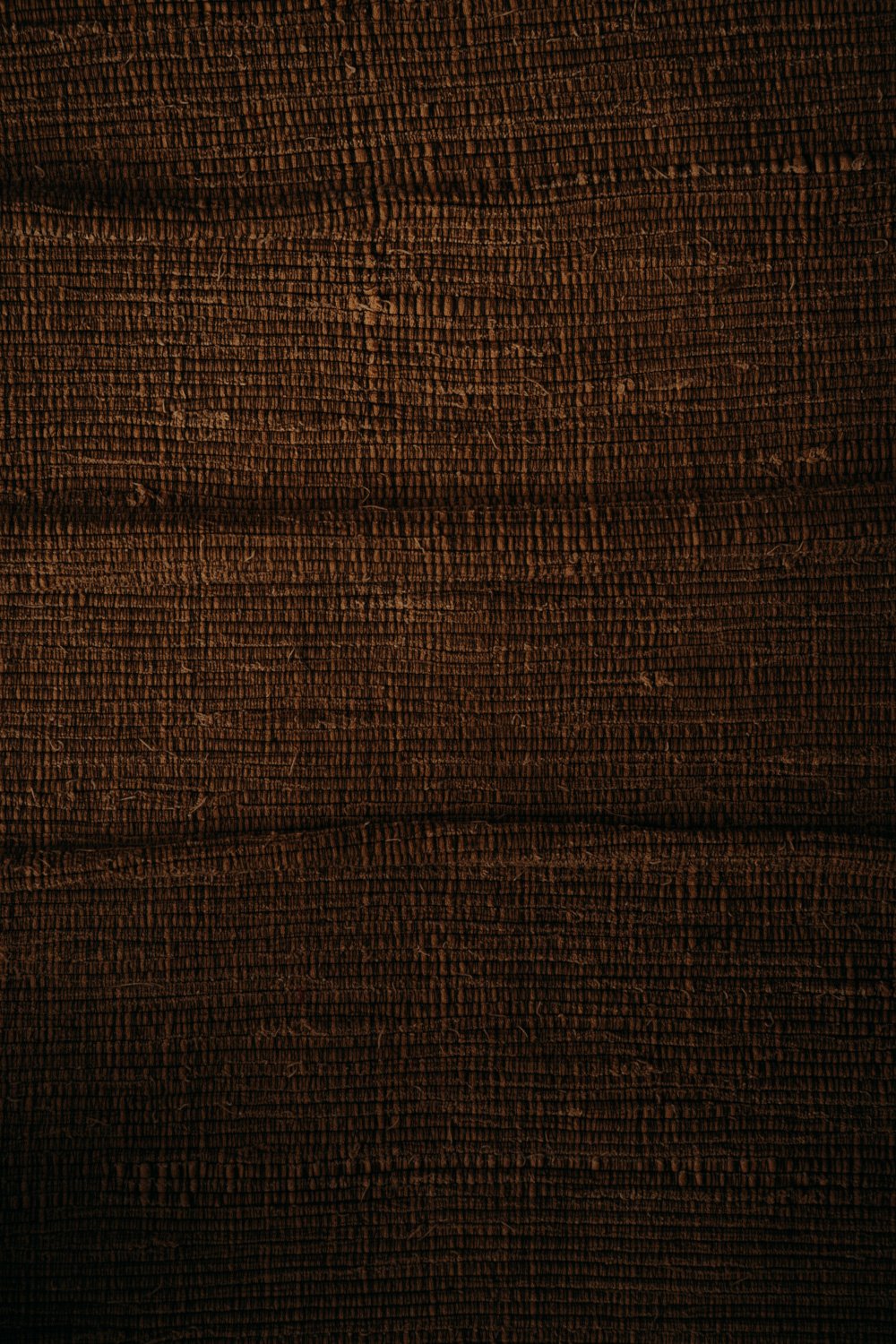 Nahaufnahme von dunklem Holz mit sichtbarer Maserung und Textur.