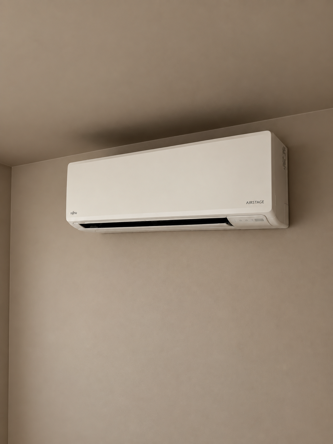 A wall-mounted, white Fujitsu Airstage air conditioning unit on a beige wall.