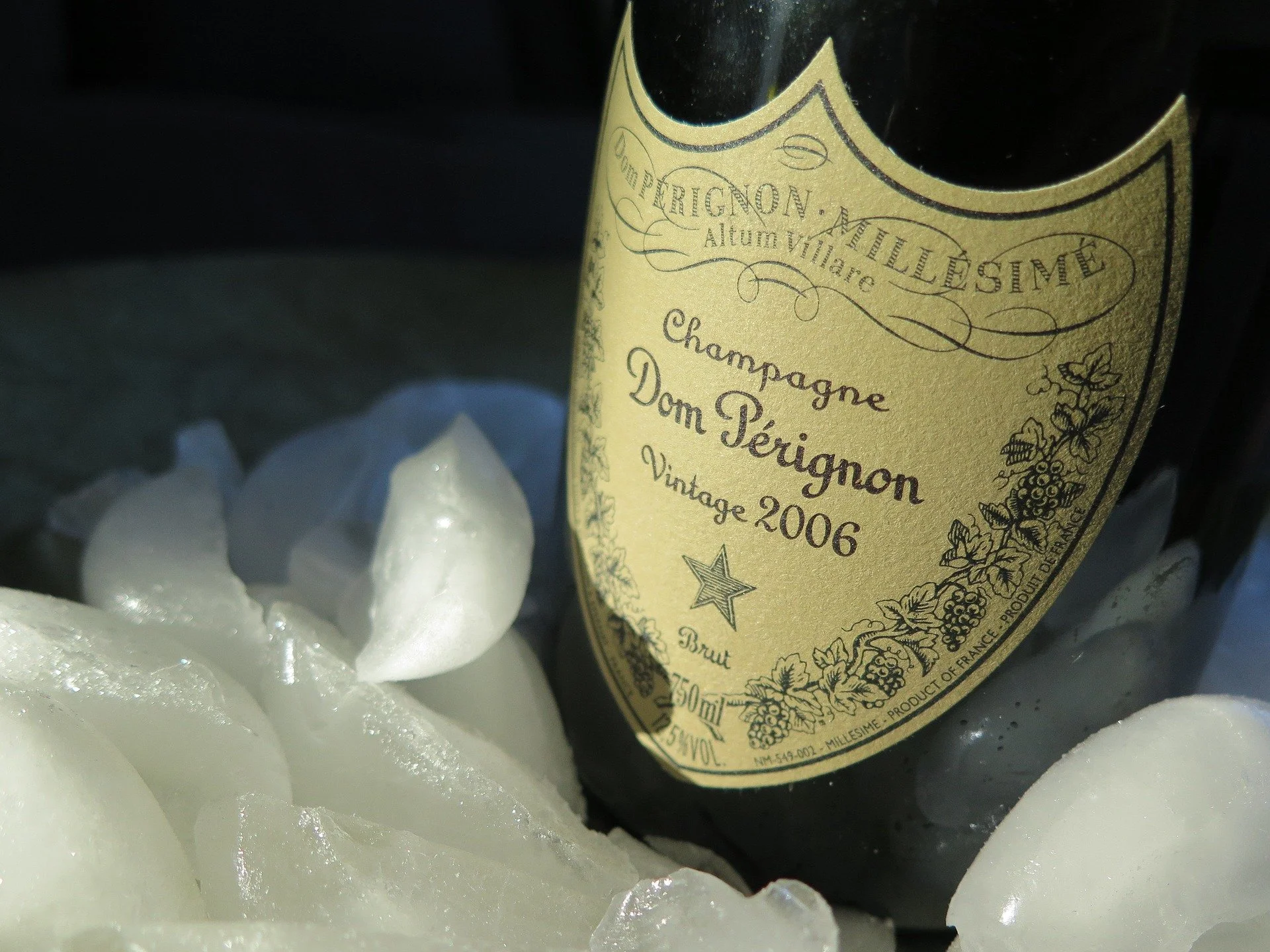 A close-up of a black bottle of Dom Pérignon champagne surrounded by ice.