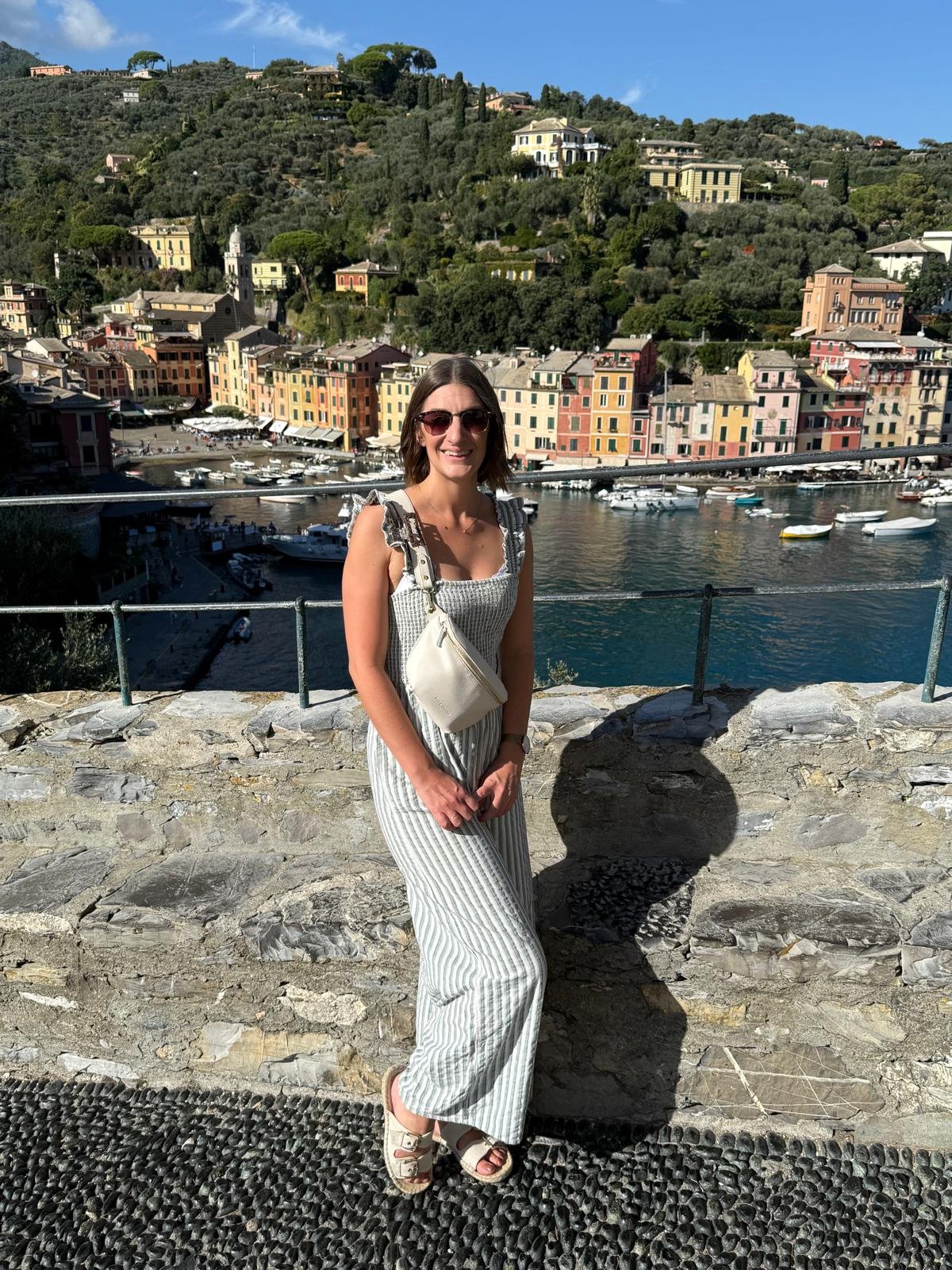 Erin Claire Butler smiling in front of a colourful Italian harbour — running a location-independent business from Scotland