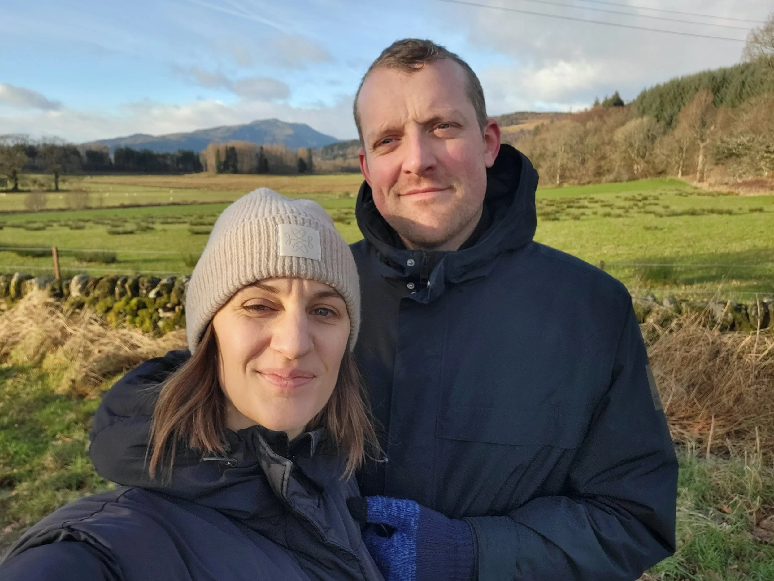 Erin Claire Butler and John smiling outdoors in the Scottish countryside