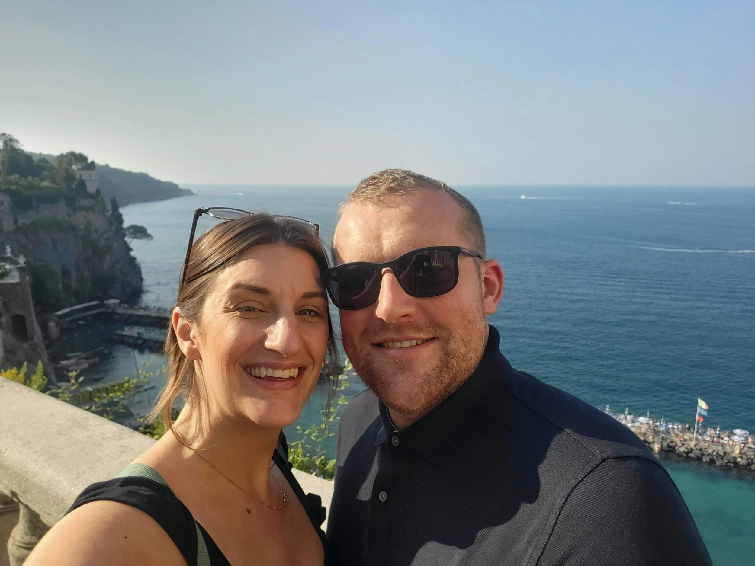 Erin Claire Butler and John smiling by the sea on an adventure in Italy