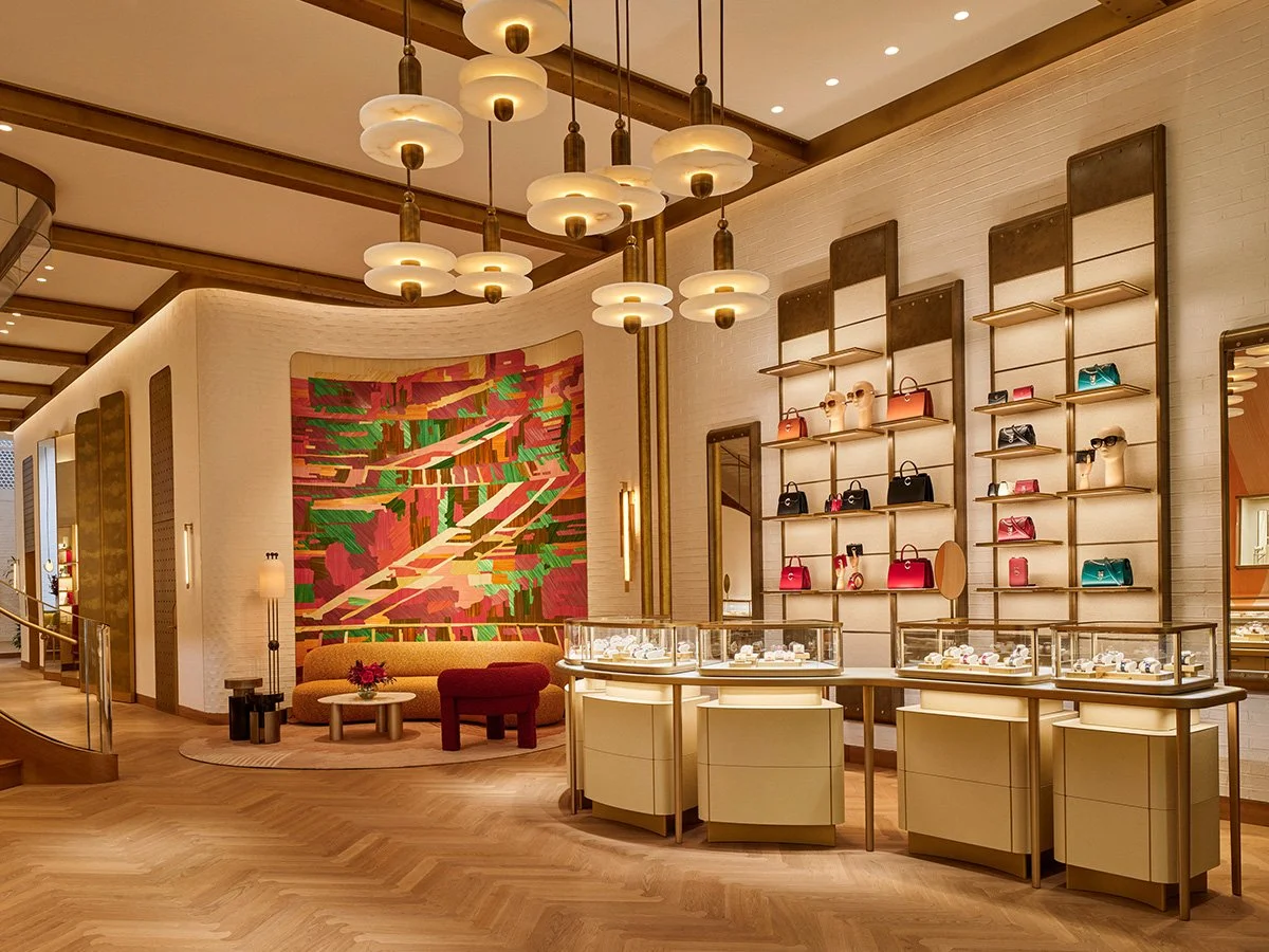 Luxurious store interior displaying handbags and accessories, with warm lighting, modern decor, and a colorful abstract wall art piece.