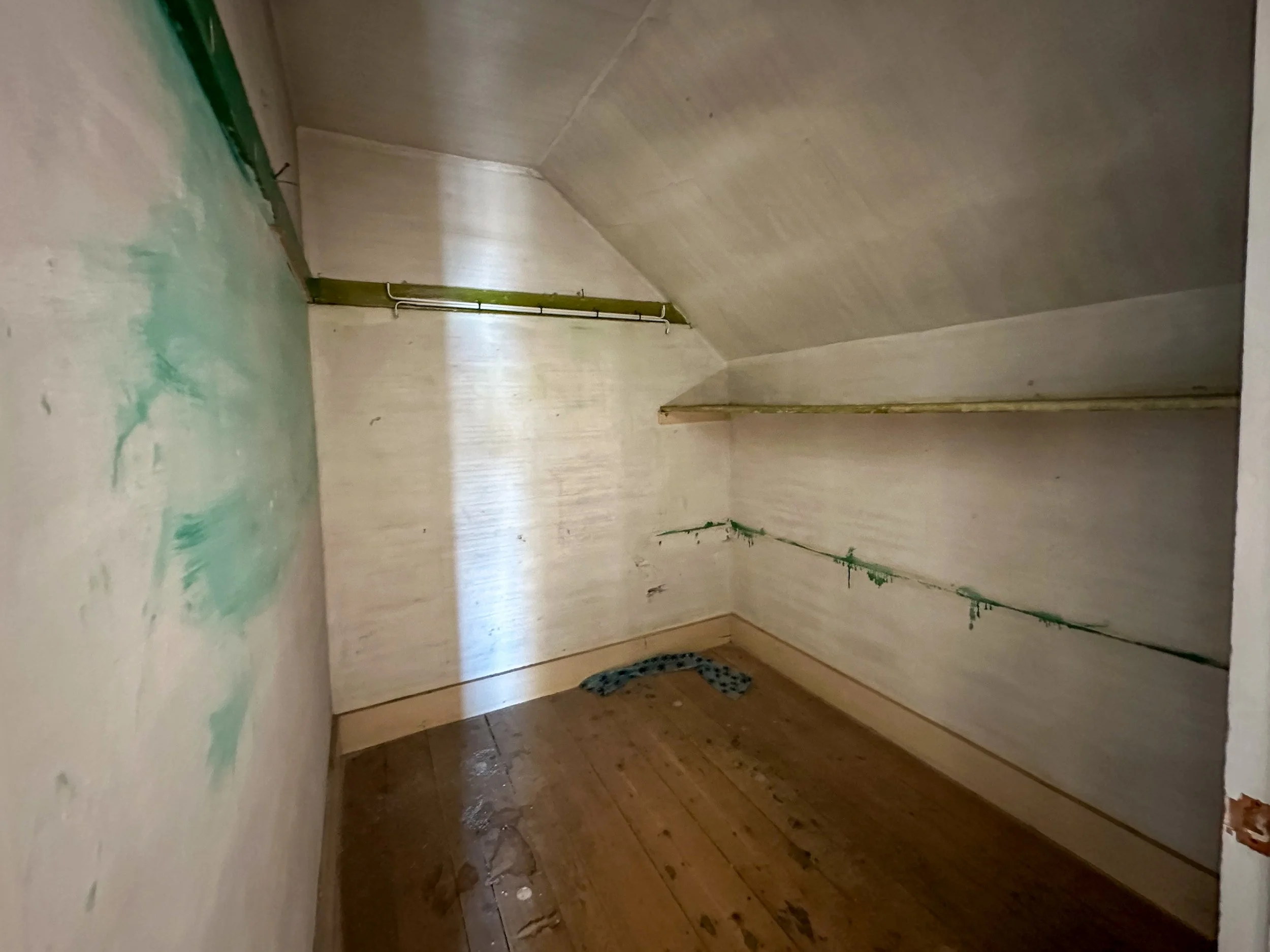 Empty room with unfinished walls, visible pipes, and a wooden floor, appearing under renovation.