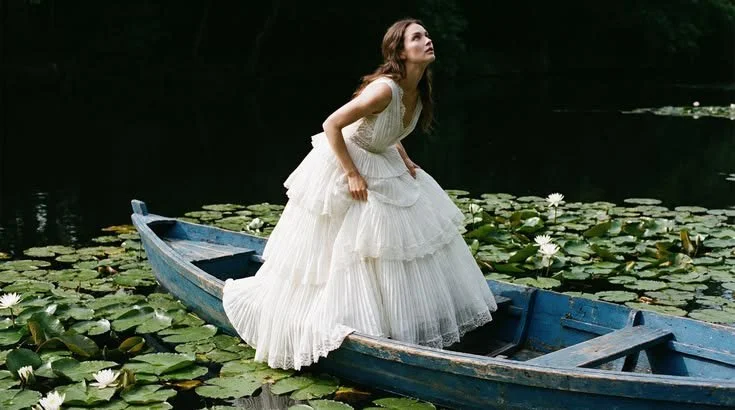 Bride on a lake surrounded by water lilies in editorial wedding concept