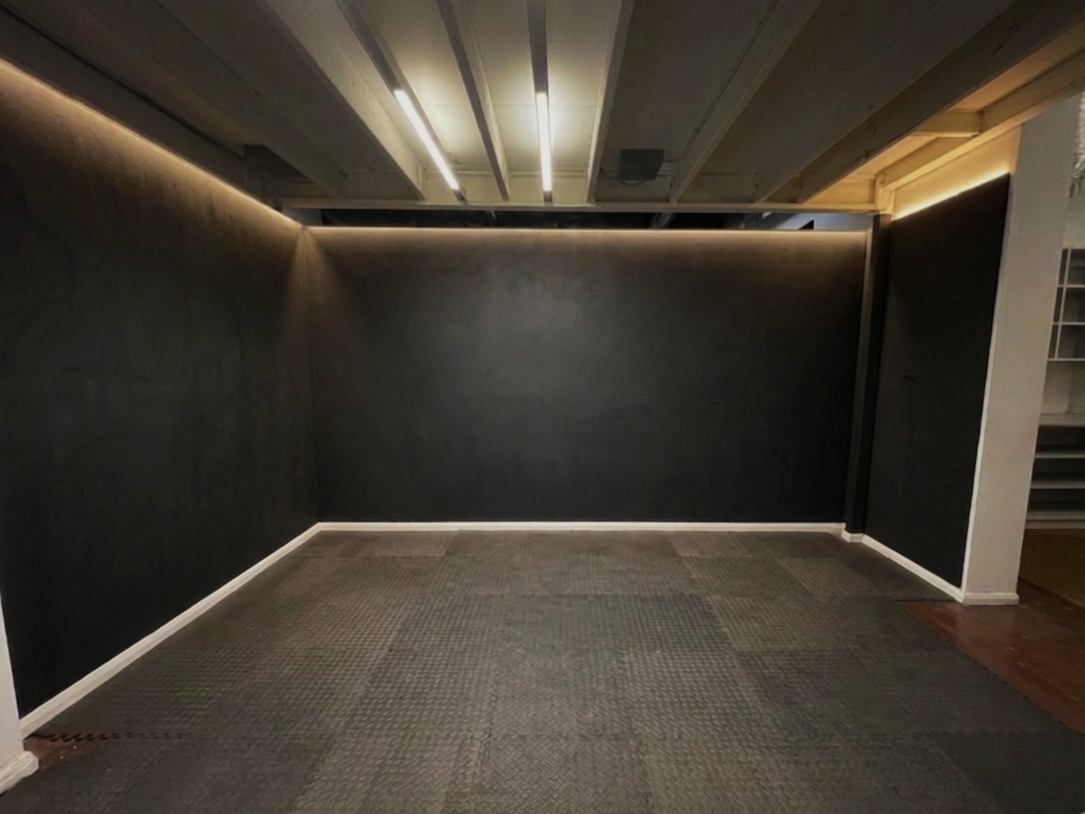 Empty room with dark walls, ceiling lights, and a partially visible doorway to the right.